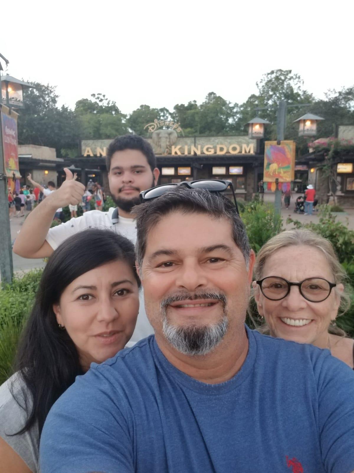 Four friends smile at the animal kingdom entrance, enjoying joyful moments at dusk.