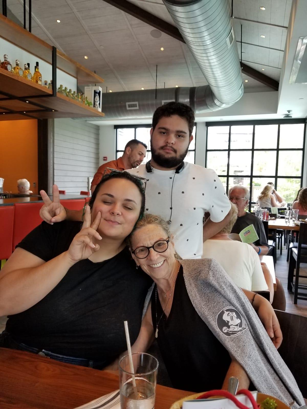 Two friends pose for a playful photo while a server smiles in the background.