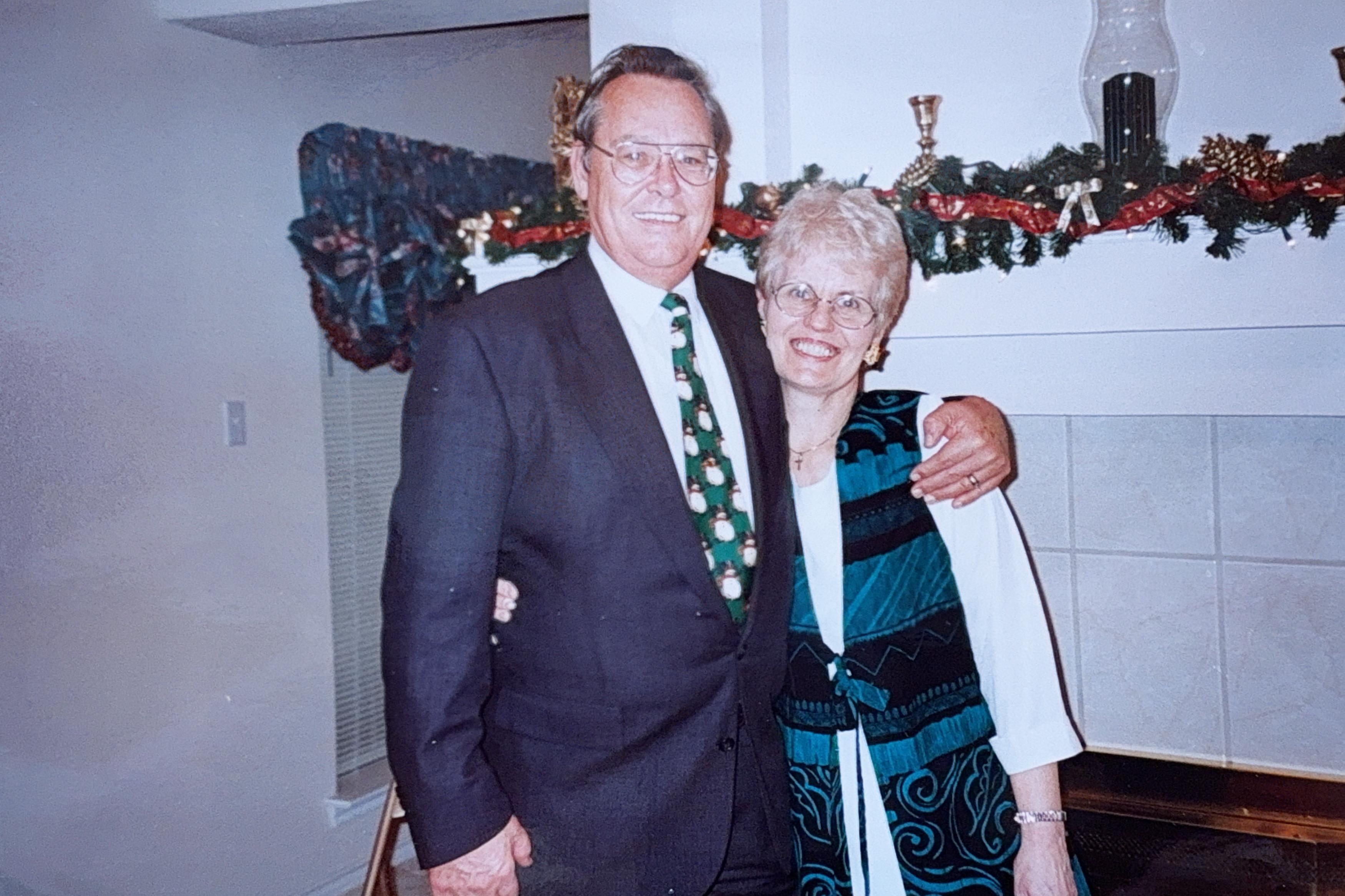 A happy couple stands closely together in a decorated living room during a festive occasion.