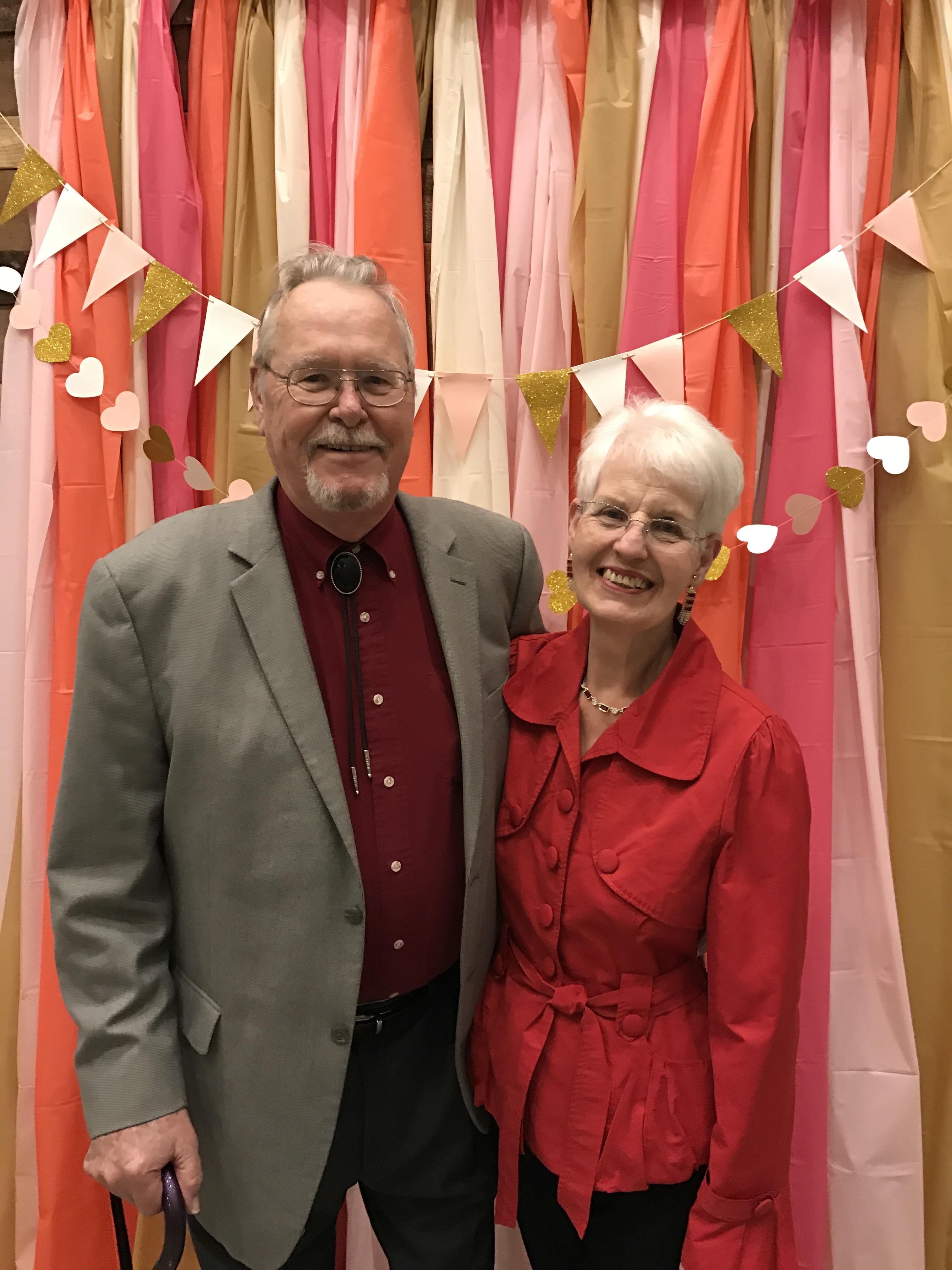 Loving couple posing happily at a vibrant indoor celebration with colorful decorations.