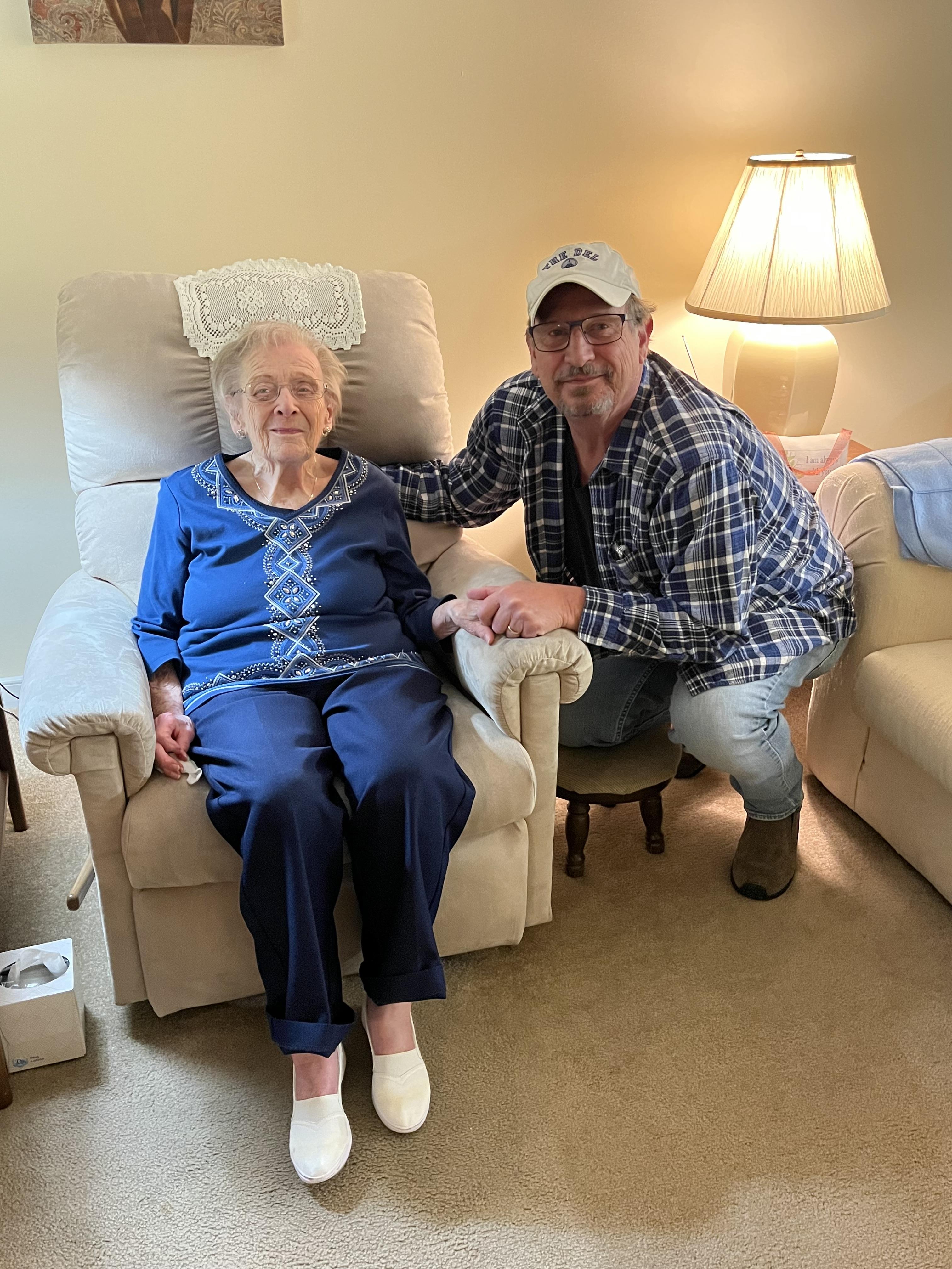 A man and an elderly woman share a warm moment together in a comfortable seating area.