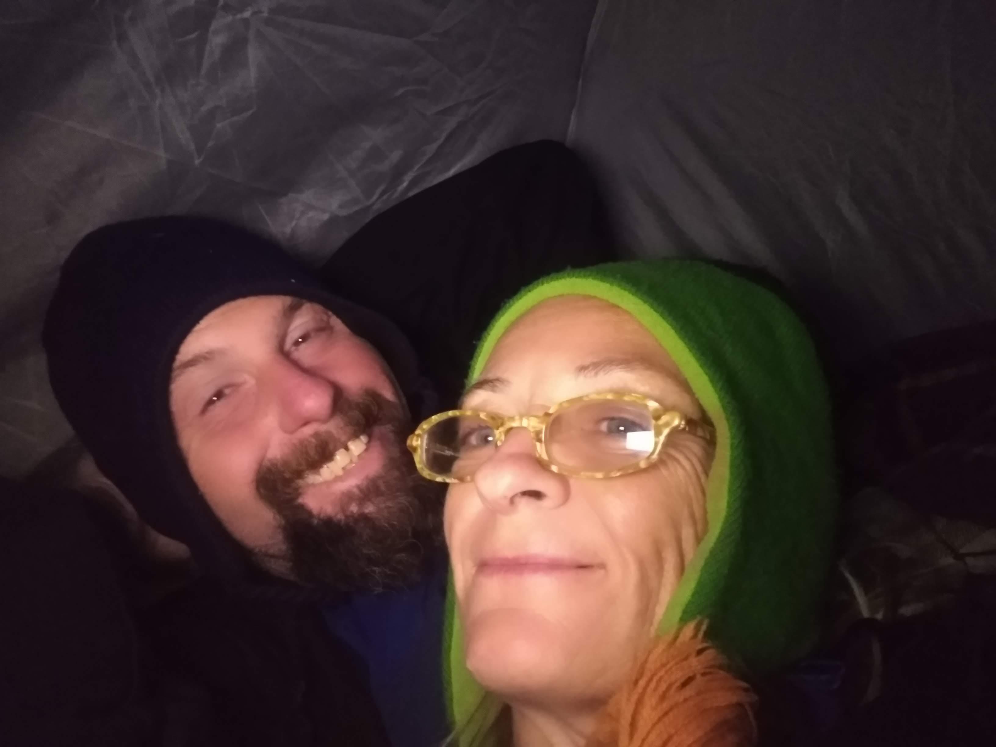 Couple shares a joyful moment inside a tent, illuminated by soft lighting, while camping.