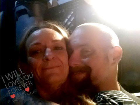 Two people share a warm embrace and smiles in a dimly lit setting, radiating love and affection.