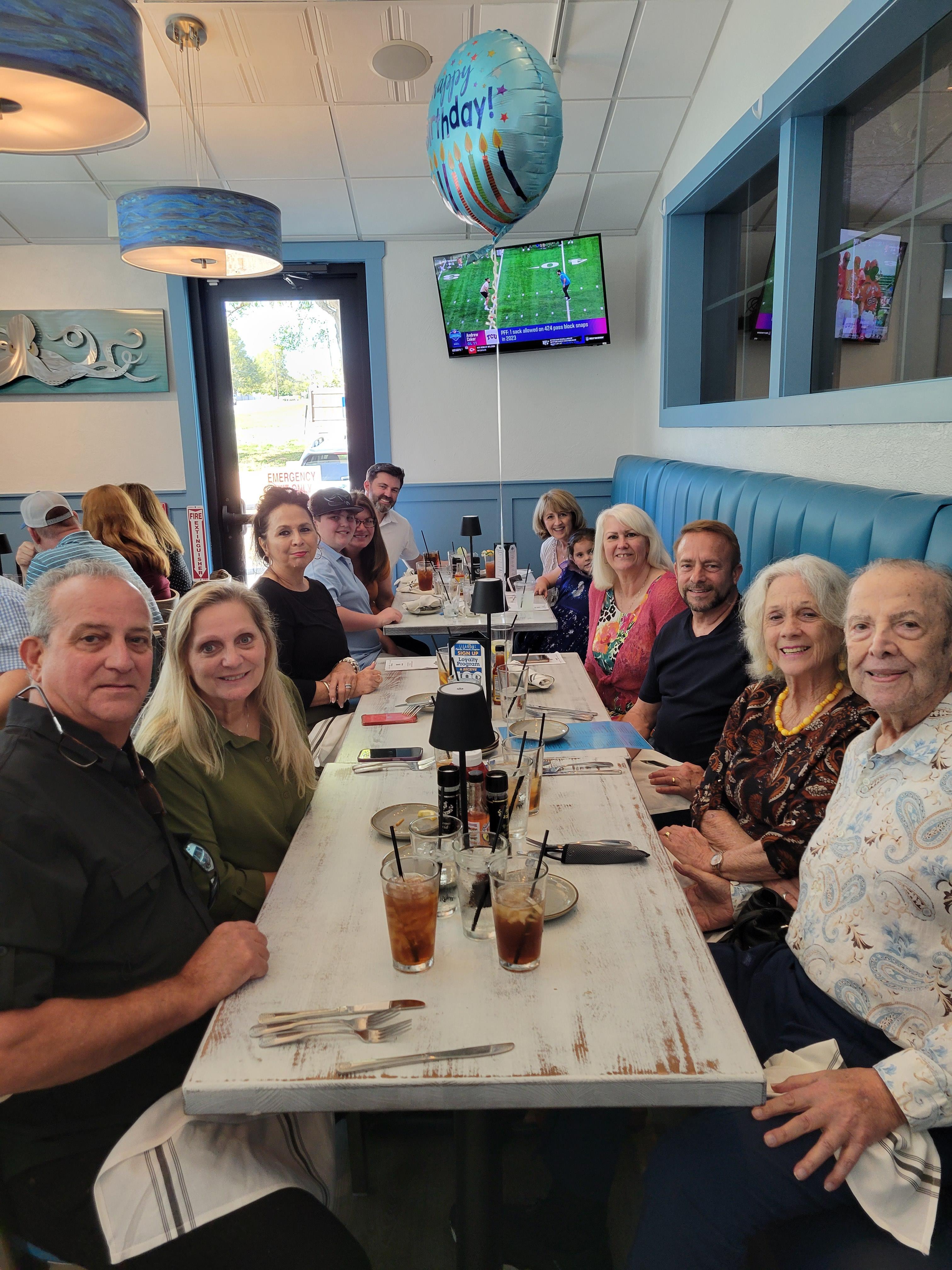 A cheerful gathering of friends and family sharing drinks and food in a lively dining area.