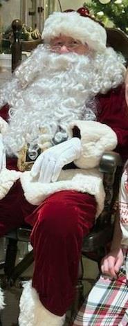 Children gather around Santa Claus, dressed in a classic suit, sharing holiday cheer together.