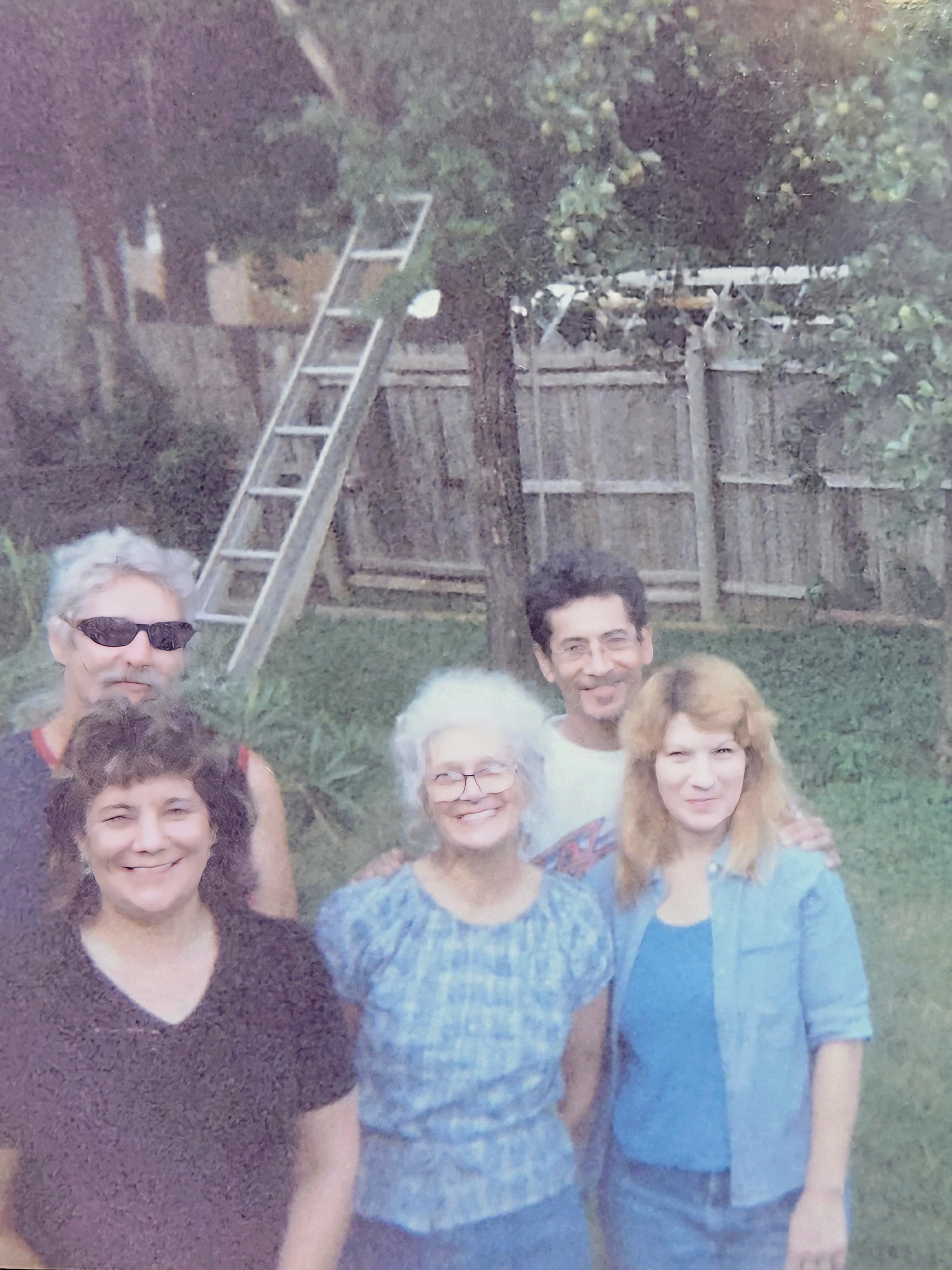 Friends and family enjoy a joyful afternoon together, posing for a cheerful group photo in the yard.