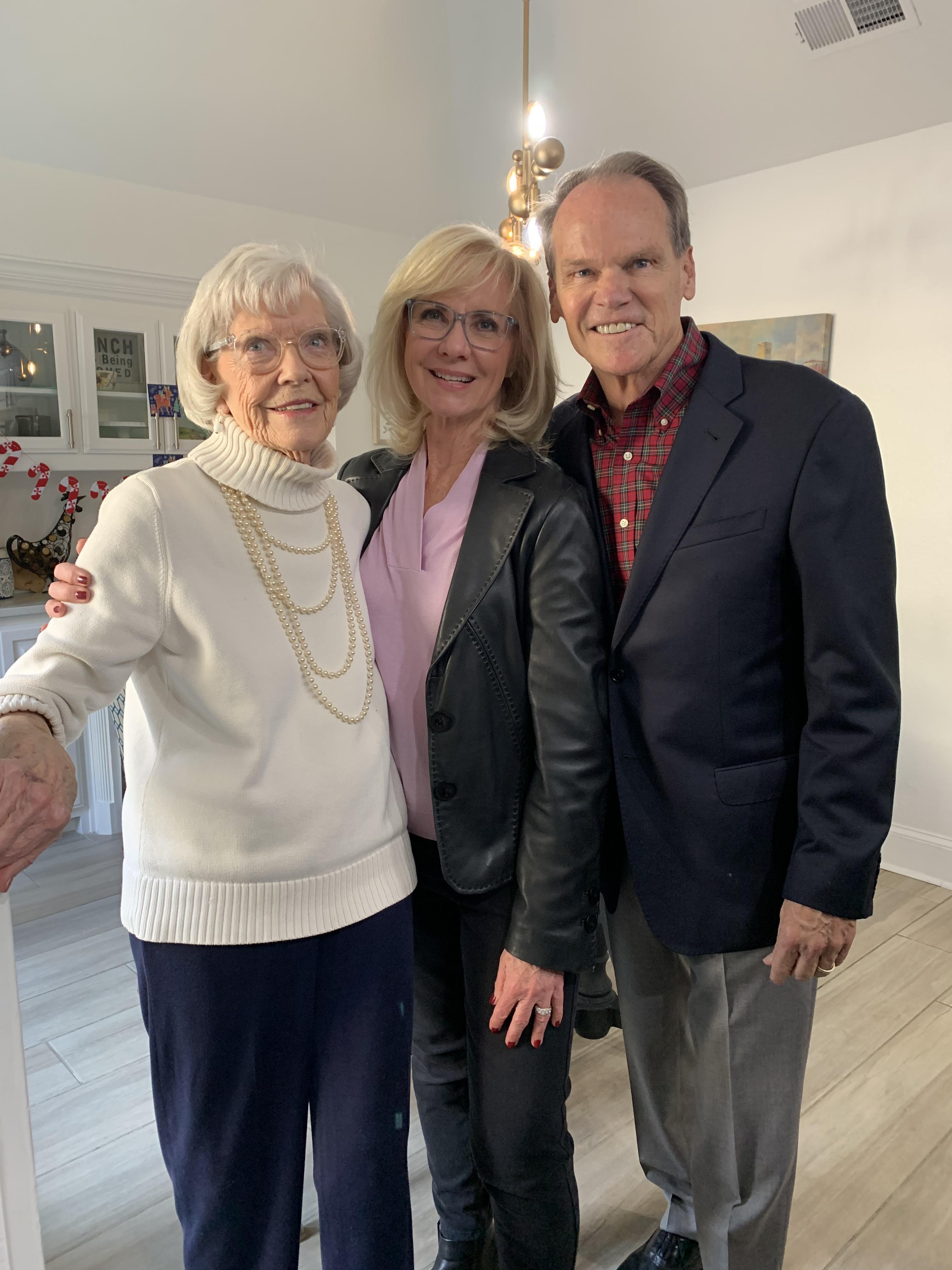 Three family members pose together in a bright, inviting room, sharing smiles and warmth.