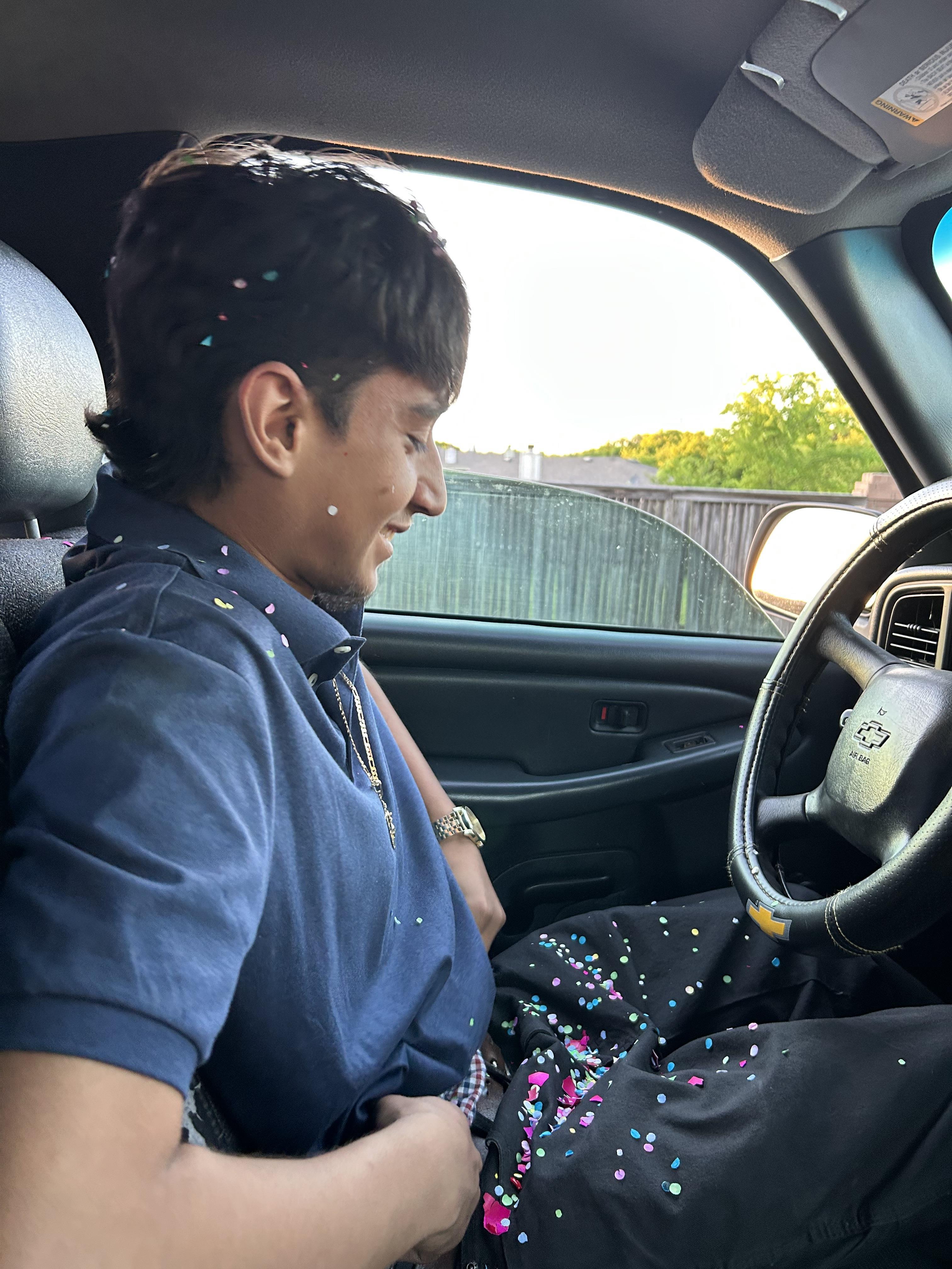 A man sitting in a car with confetti on his pants