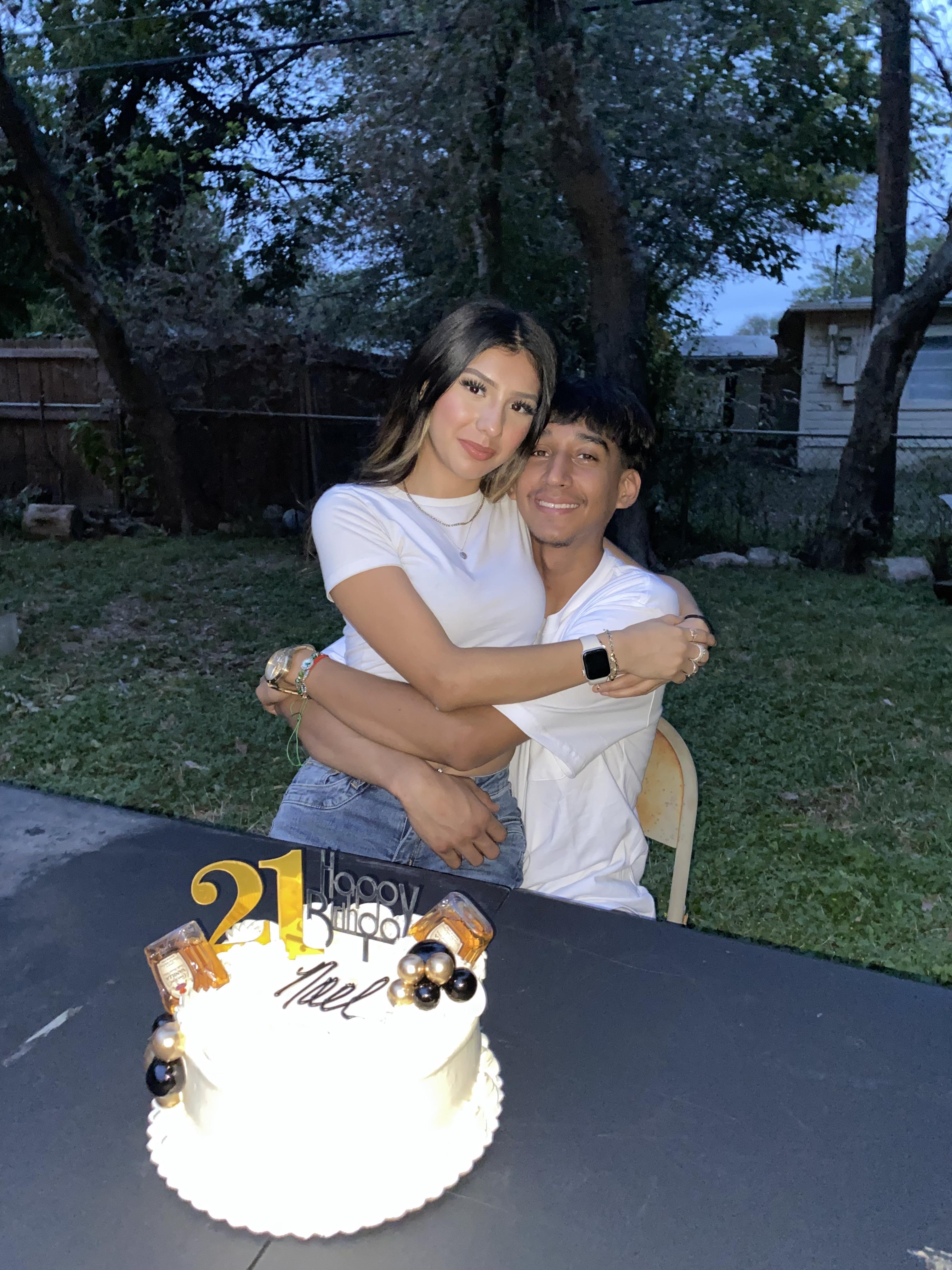 A man and woman hugging in front of a cake
