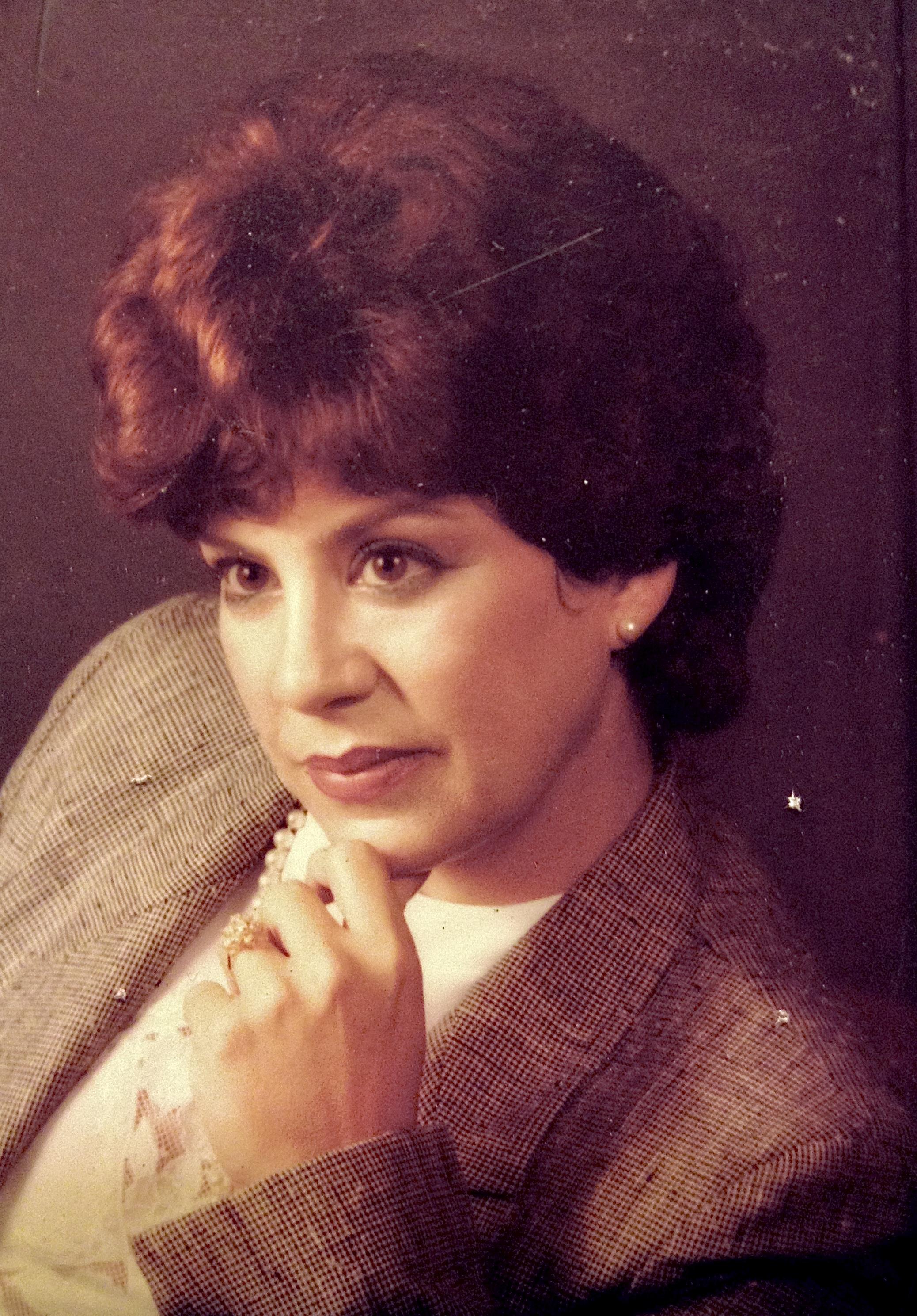 A woman with curly hair poses in a suit, showcasing confidence and contemplation.