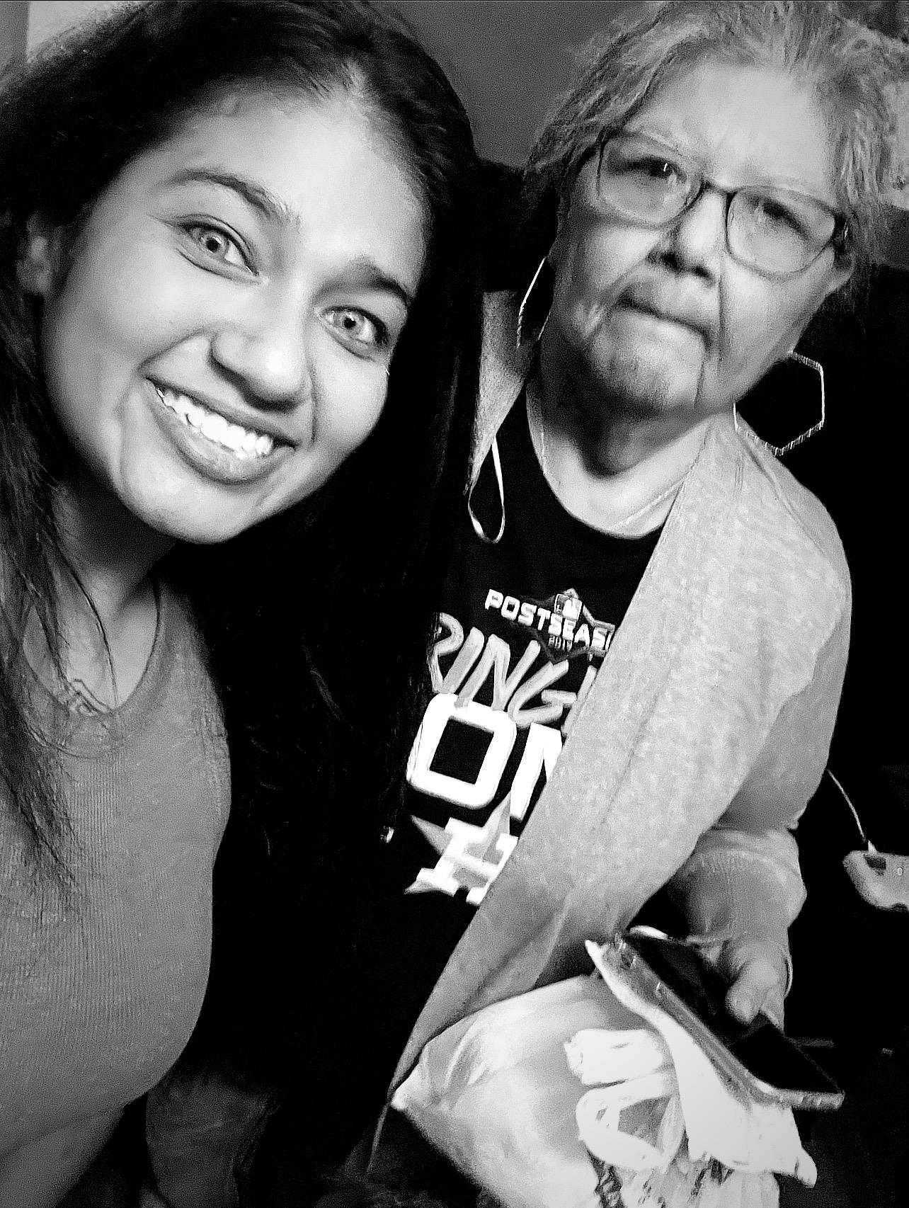 Two women share a joyful moment, smiling for a selfie during a relaxed evening gathering.