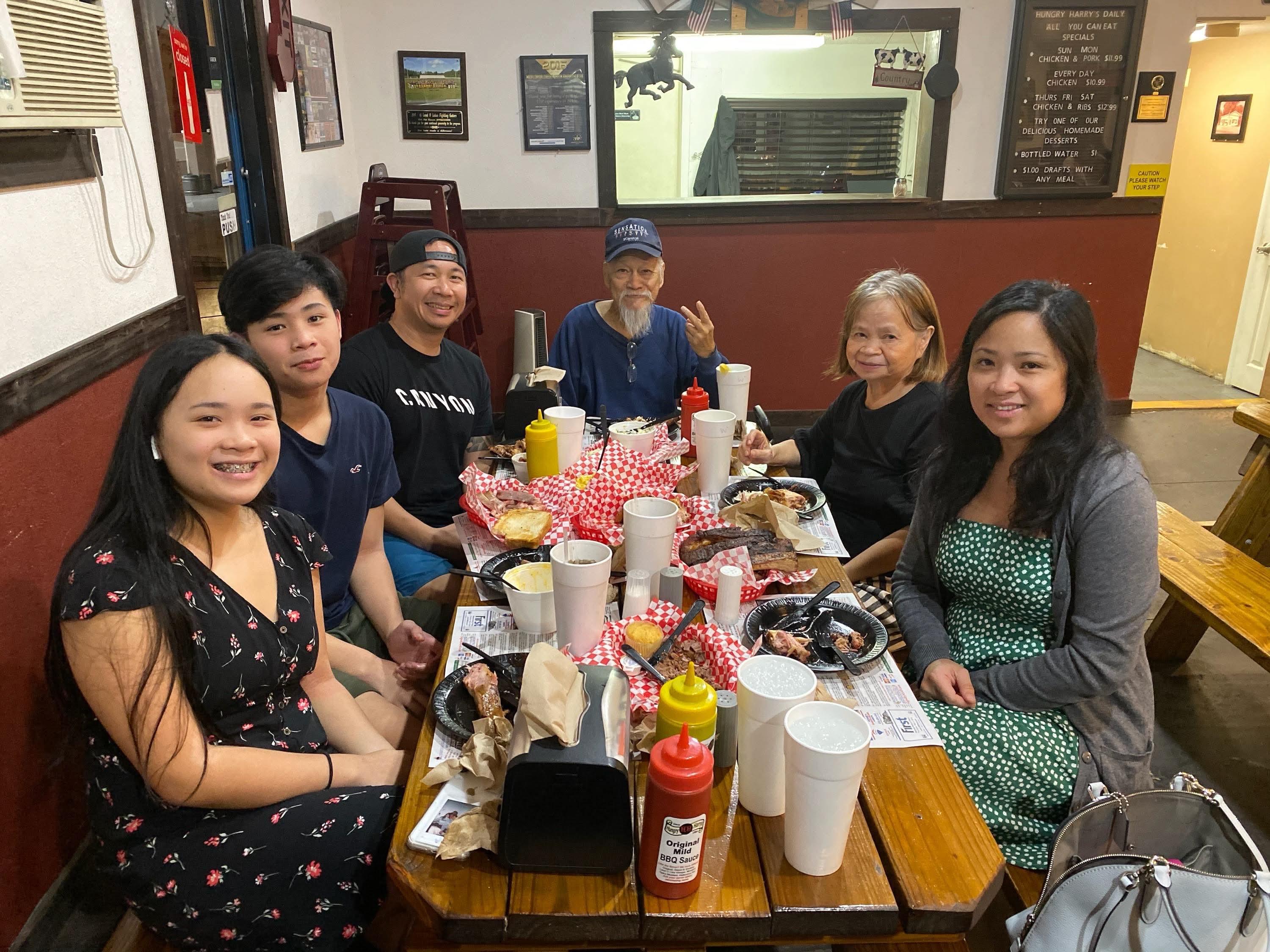 Six friends gather around a table filled with food and drinks, sharing laughter and stories.