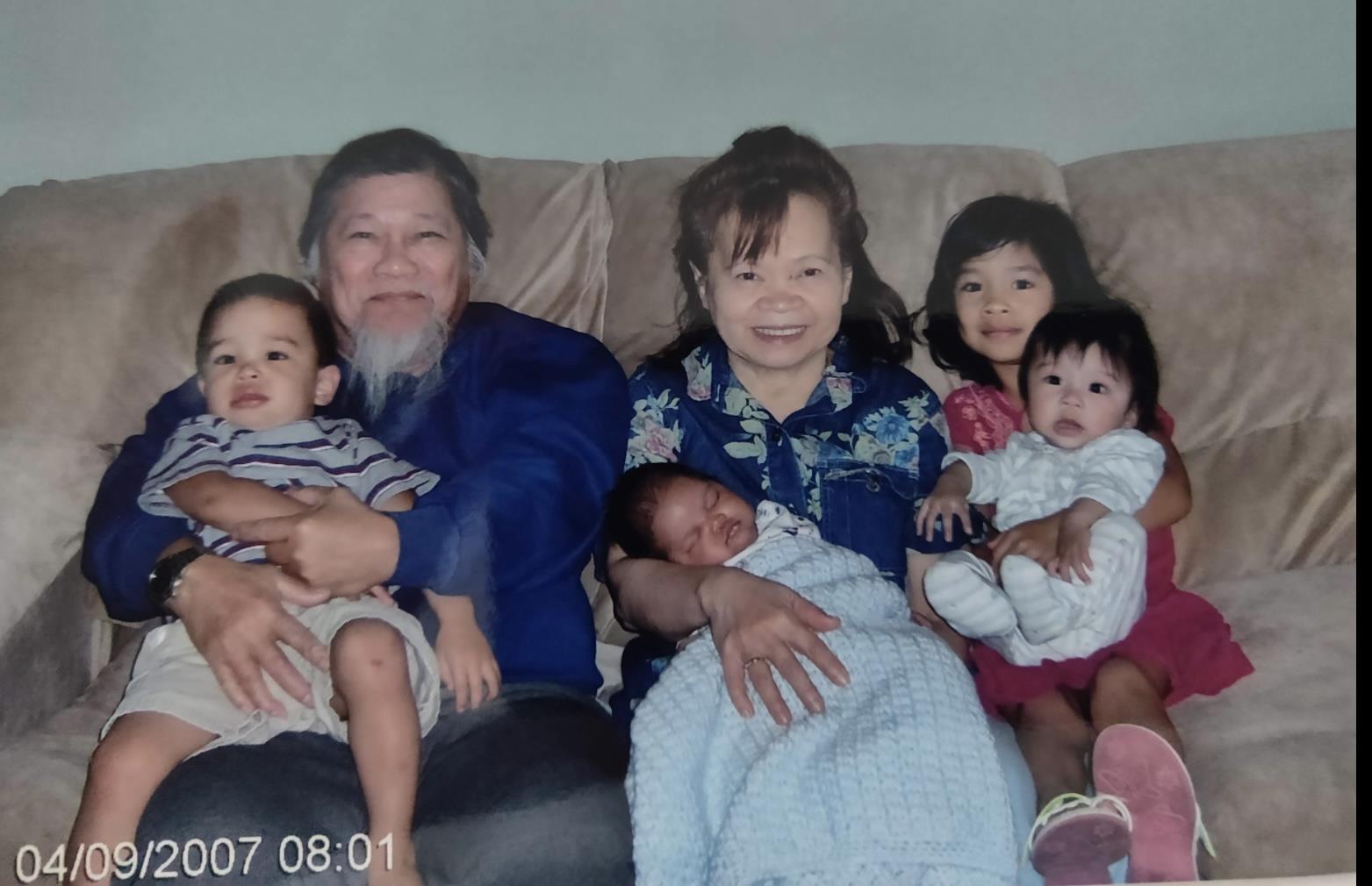 Grandparents hold their grandchildren in a warm living room while sharing smiles and joy.