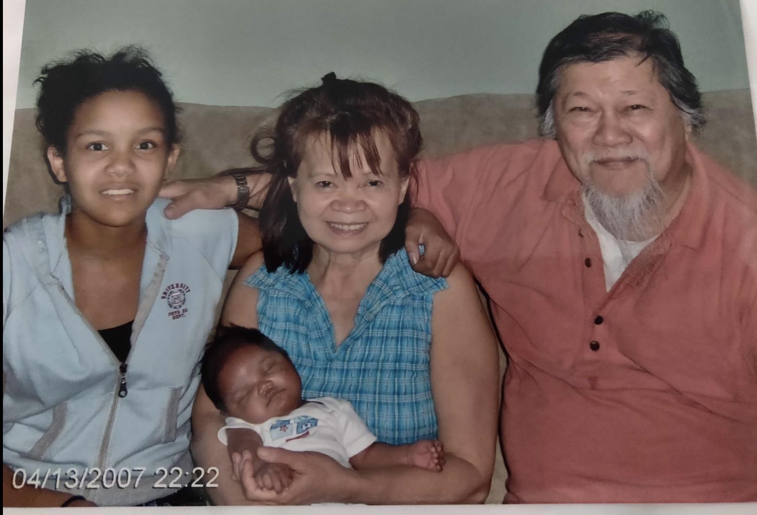 Four family members smile together, showcasing their bond with a newborn in arms.