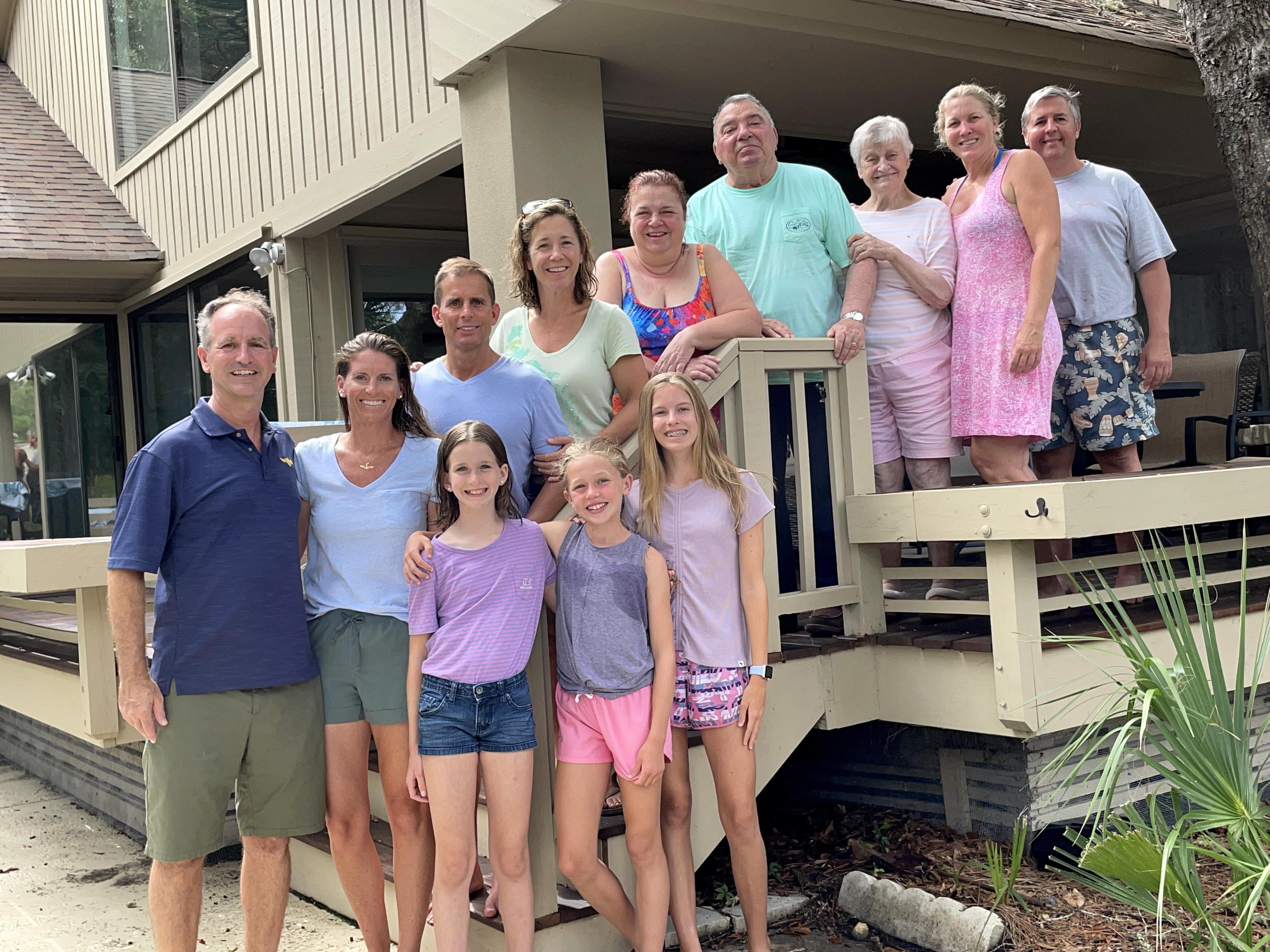 A cheerful group poses together at a vacation home, enjoying quality time during summer.