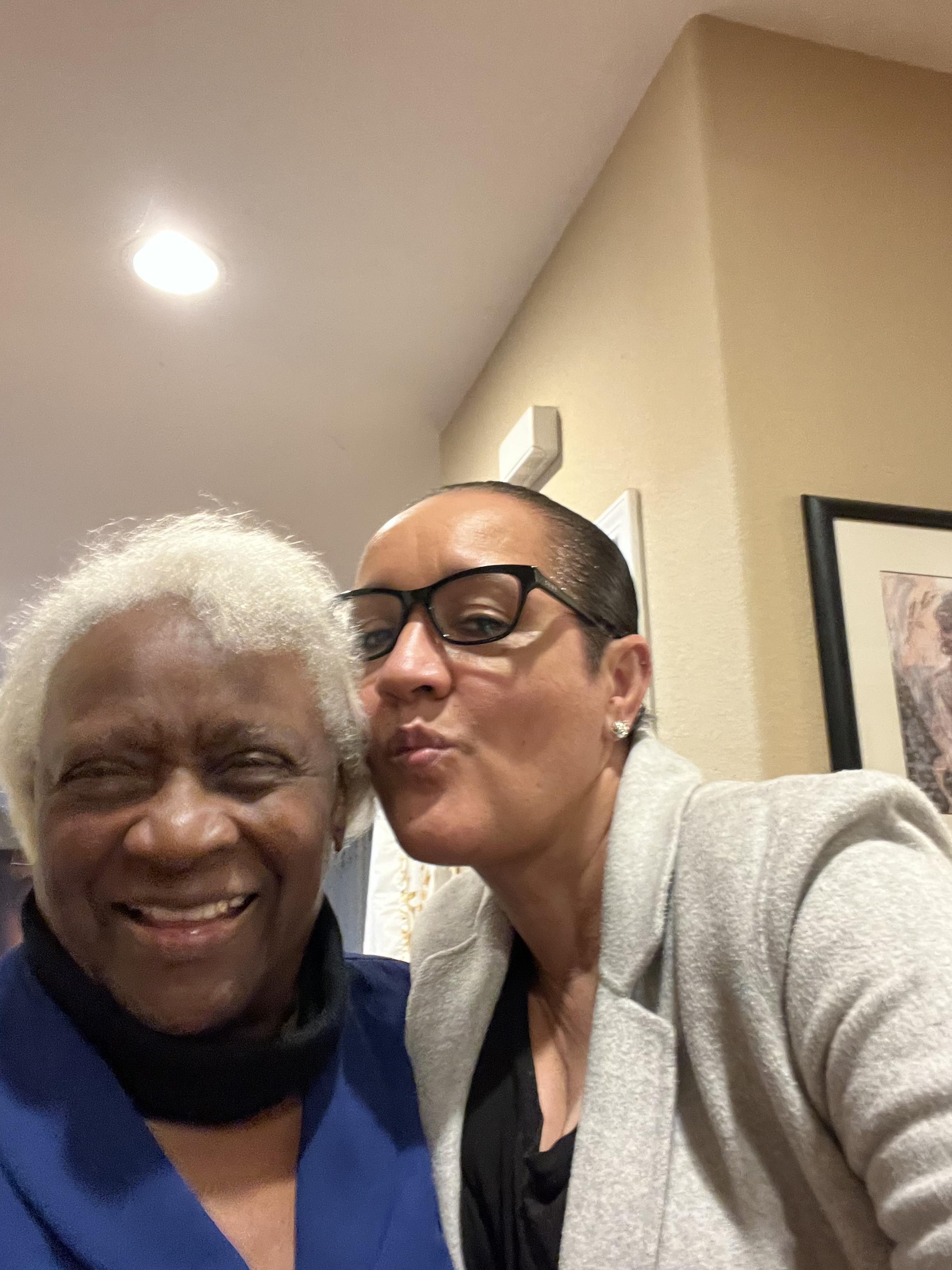 Two people are smiling and enjoying a close moment together in a warm indoor environment.