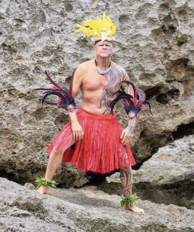 A dancer showcases cultural heritage with a colorful costume against a rocky coastal backdrop.