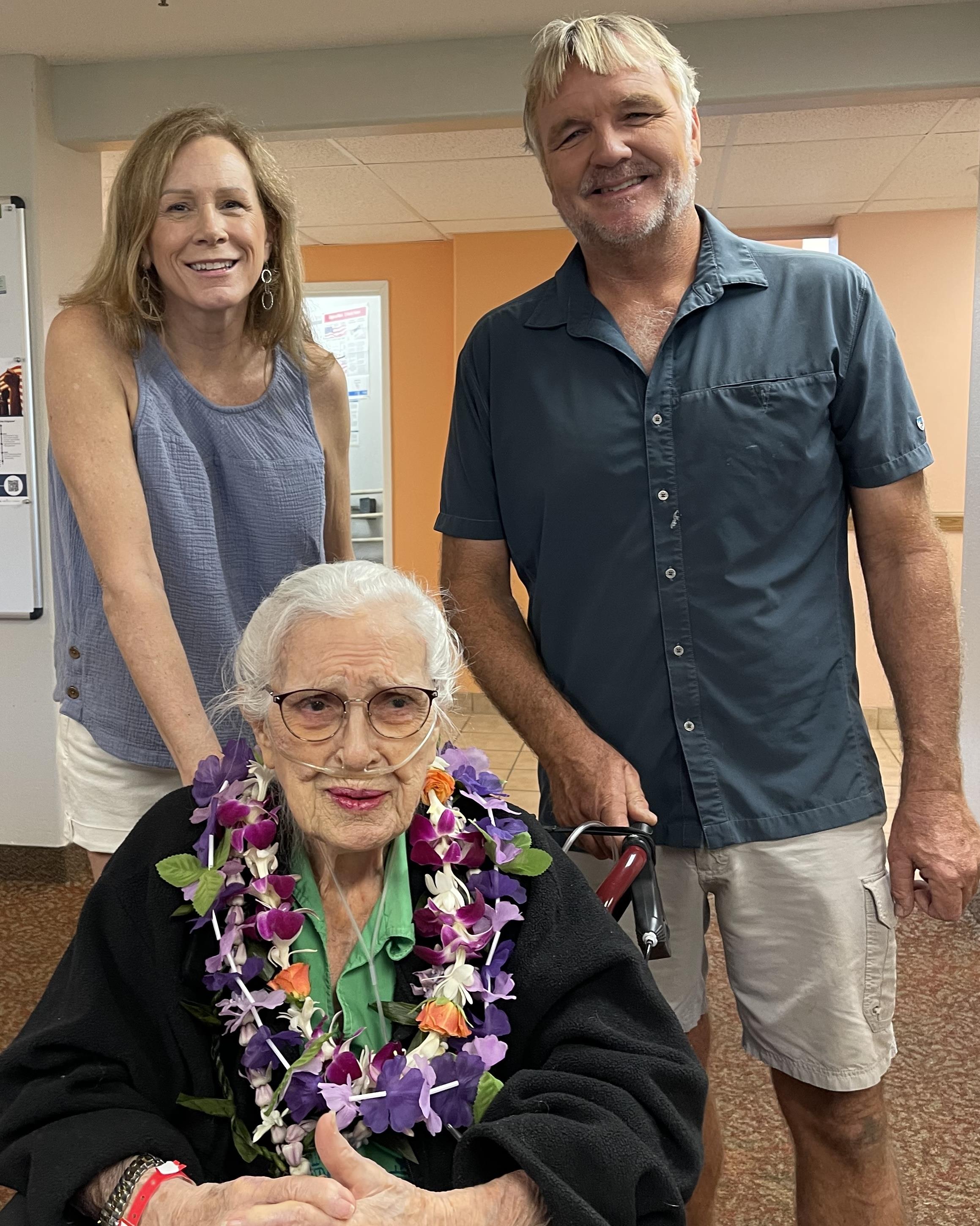 Three family members share a loving moment at a care home, showcasing their bond and happiness.