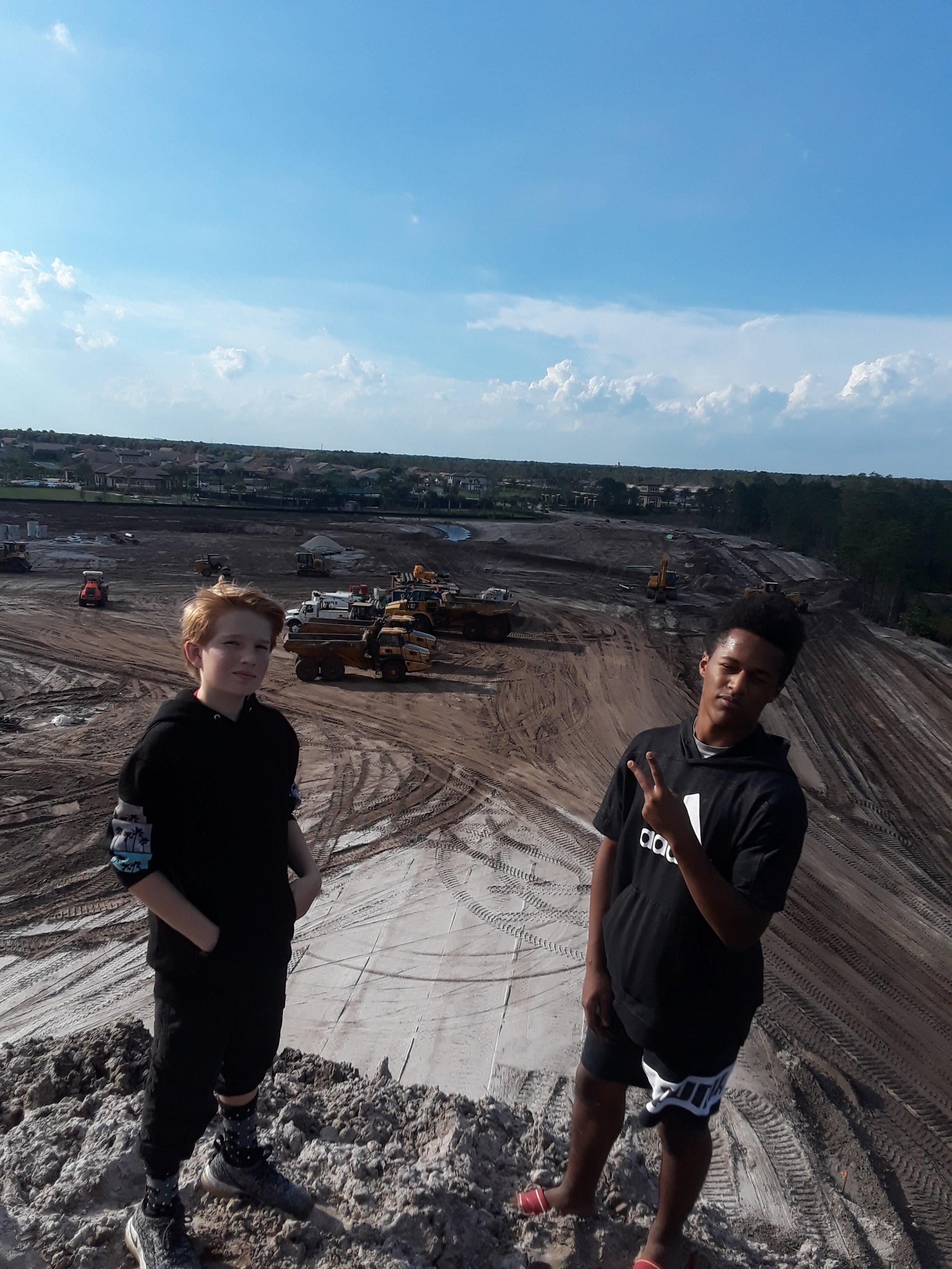 Two boys standing on a dirt hill
