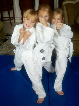 Three kids showcase their martial arts skills with determined poses on a training mat.