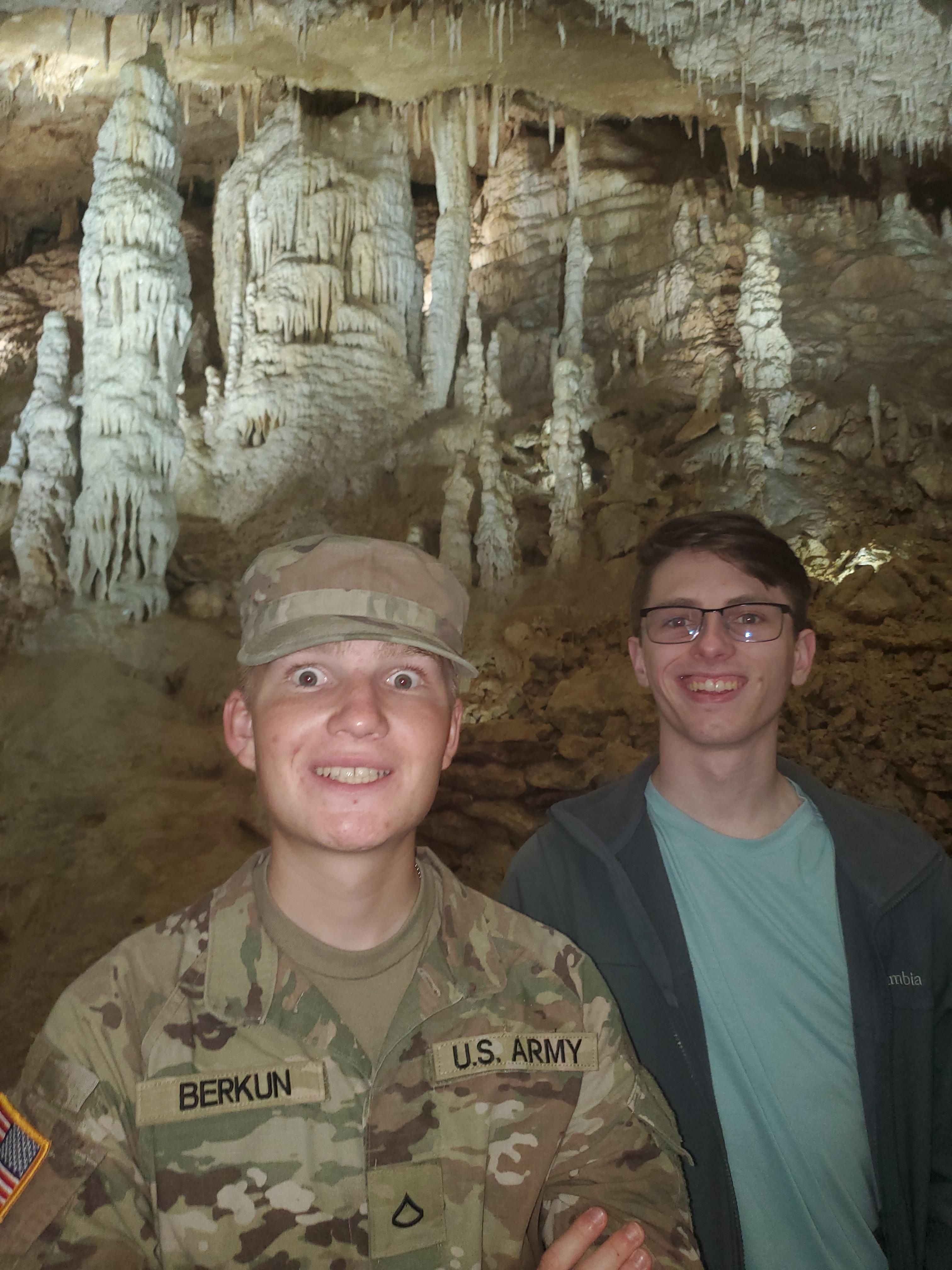Two young soldiers relax in an underground cavern with stunning rock formations.