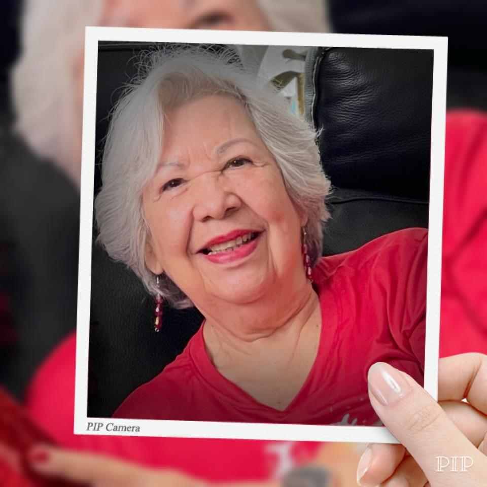An elderly woman proudly displays a cherished photograph while smiling joyfully at a gathering.