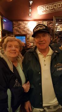 A cheerful elderly couple enjoys their time at a restaurant, smiling and holding hands.