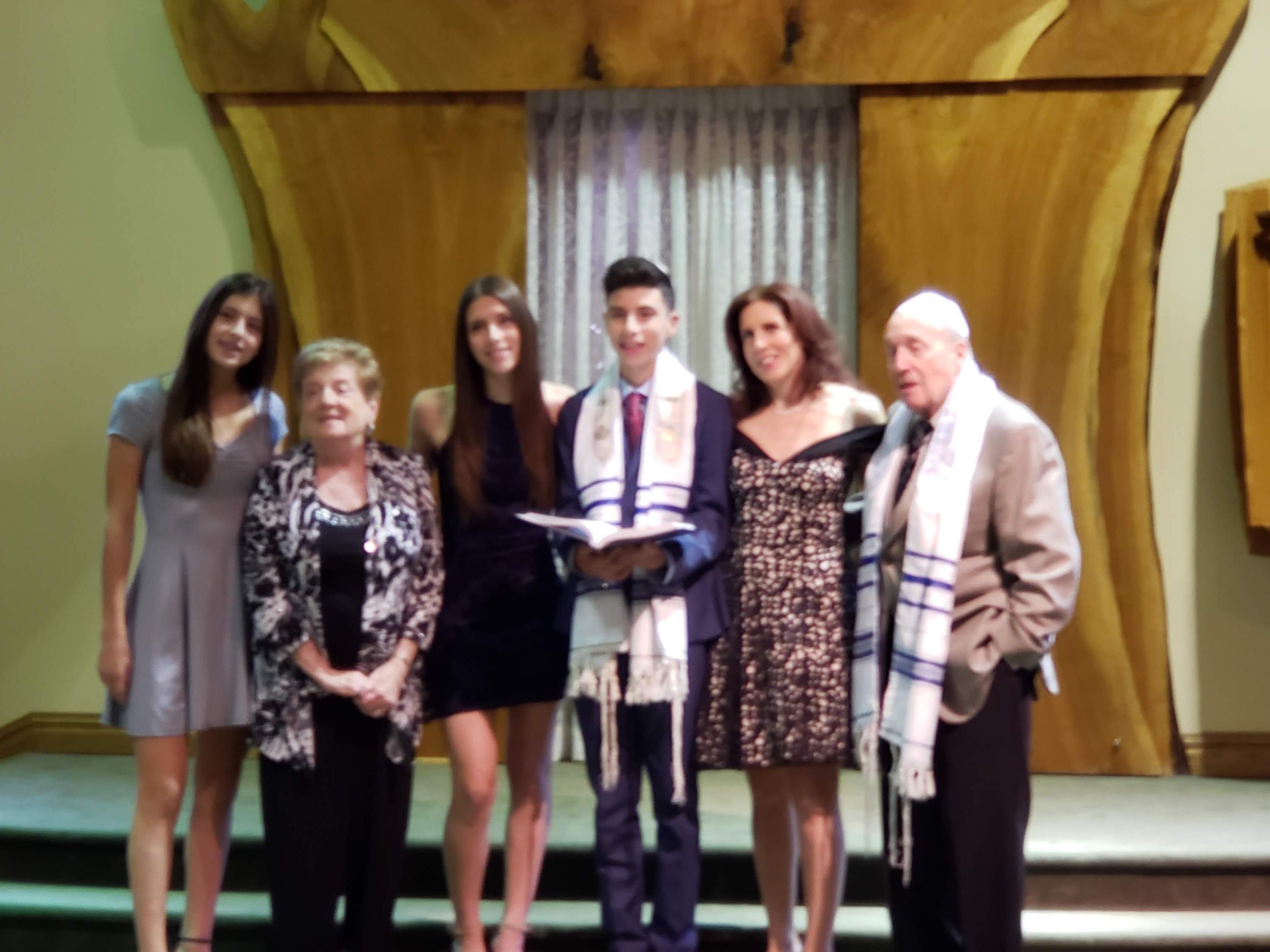 Group of family members celebrates a bar mitzvah inside a synagogue, highlighting joy and tradition.