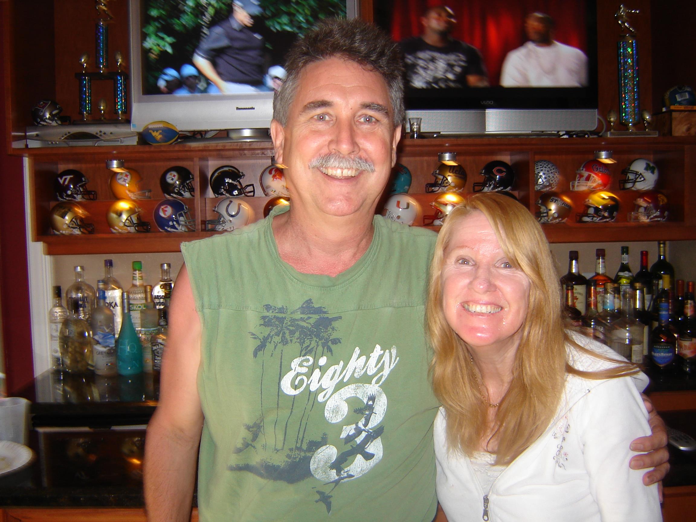 Two friends smile together at a bar, enjoying their time among memorabilia.