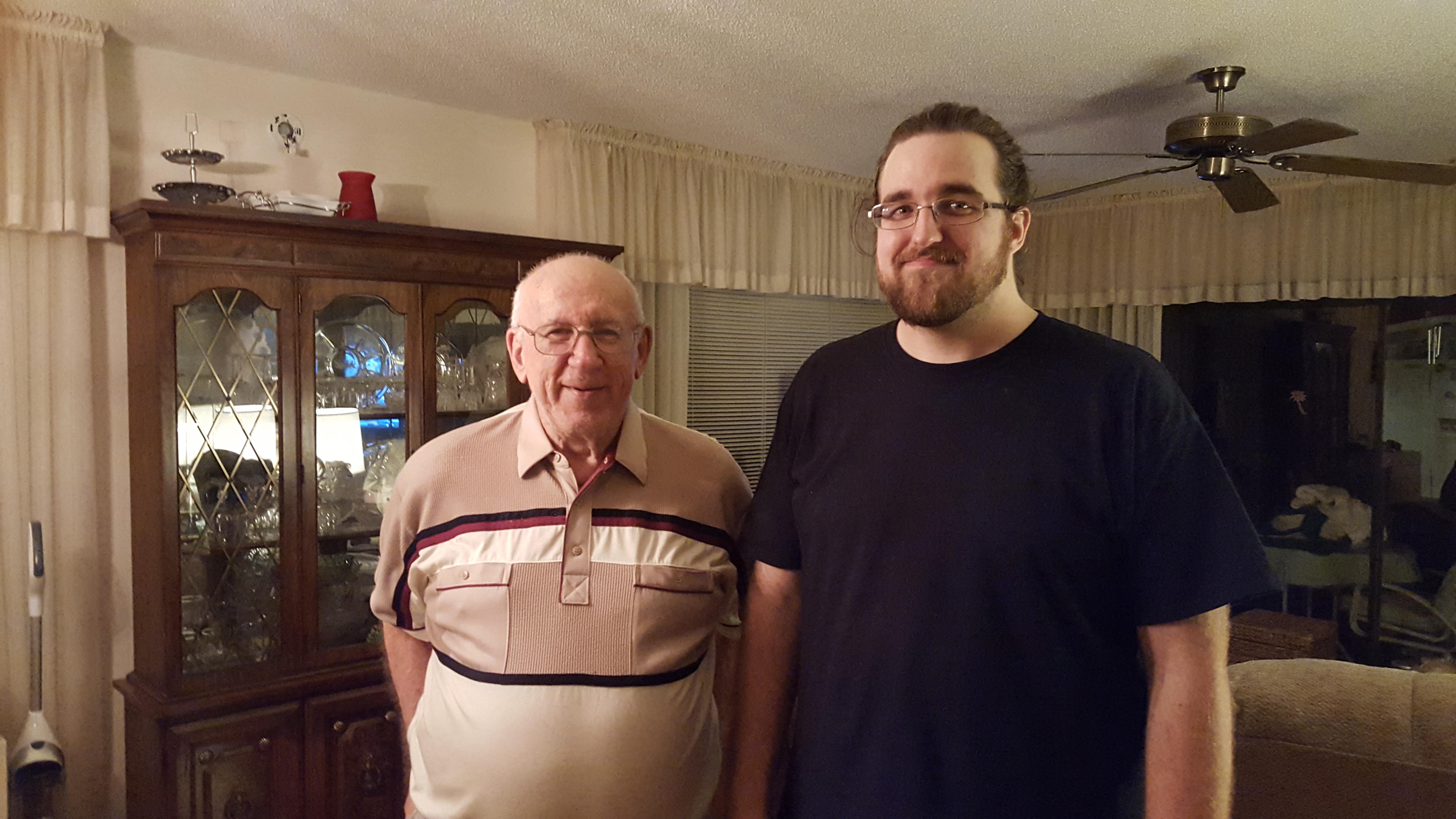 Two men of different ages smile together in a warm living room, highlighting family bonds.