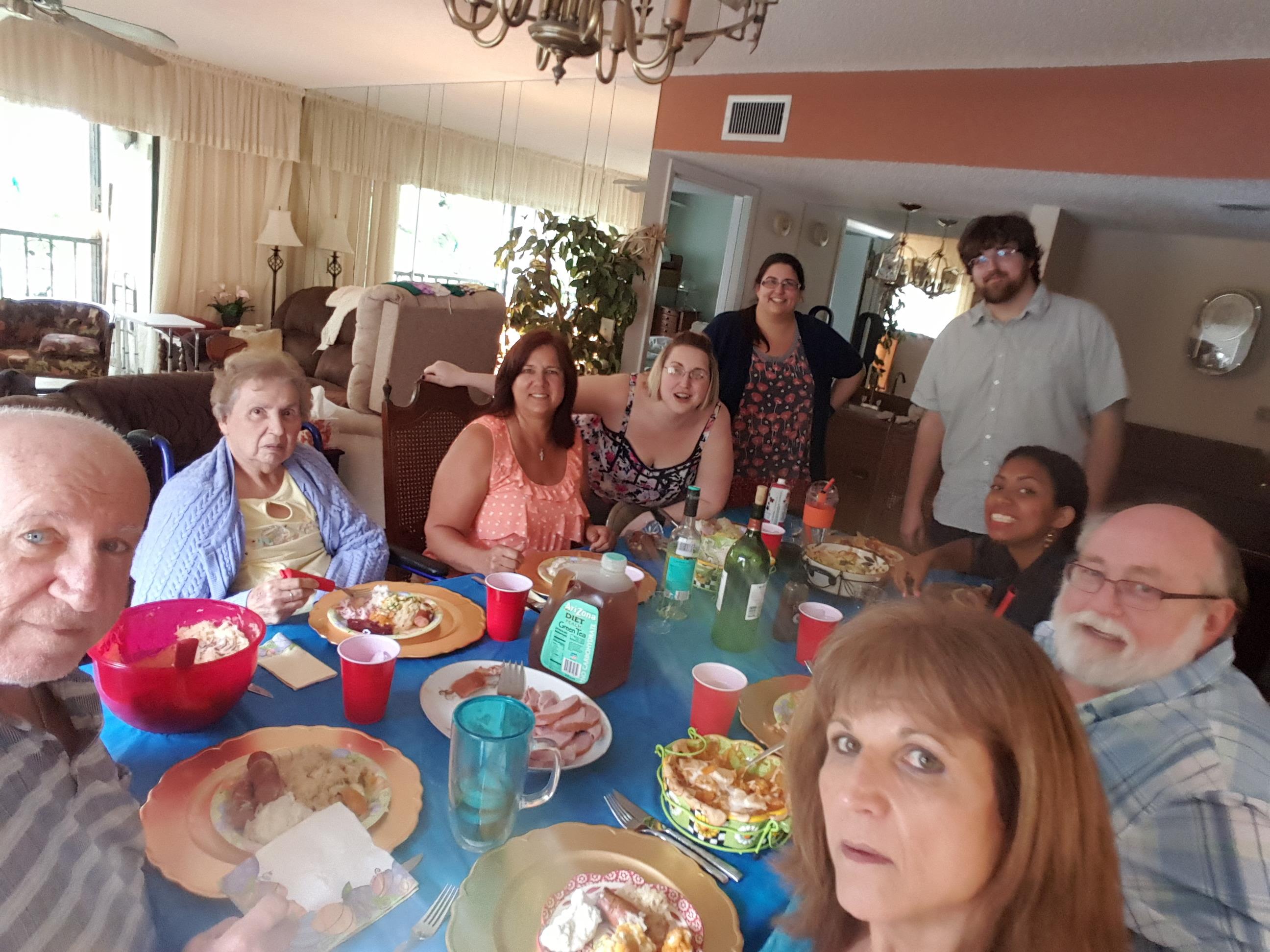 Guests gather around a table filled with dishes, enjoying each other's company and sharing stories.