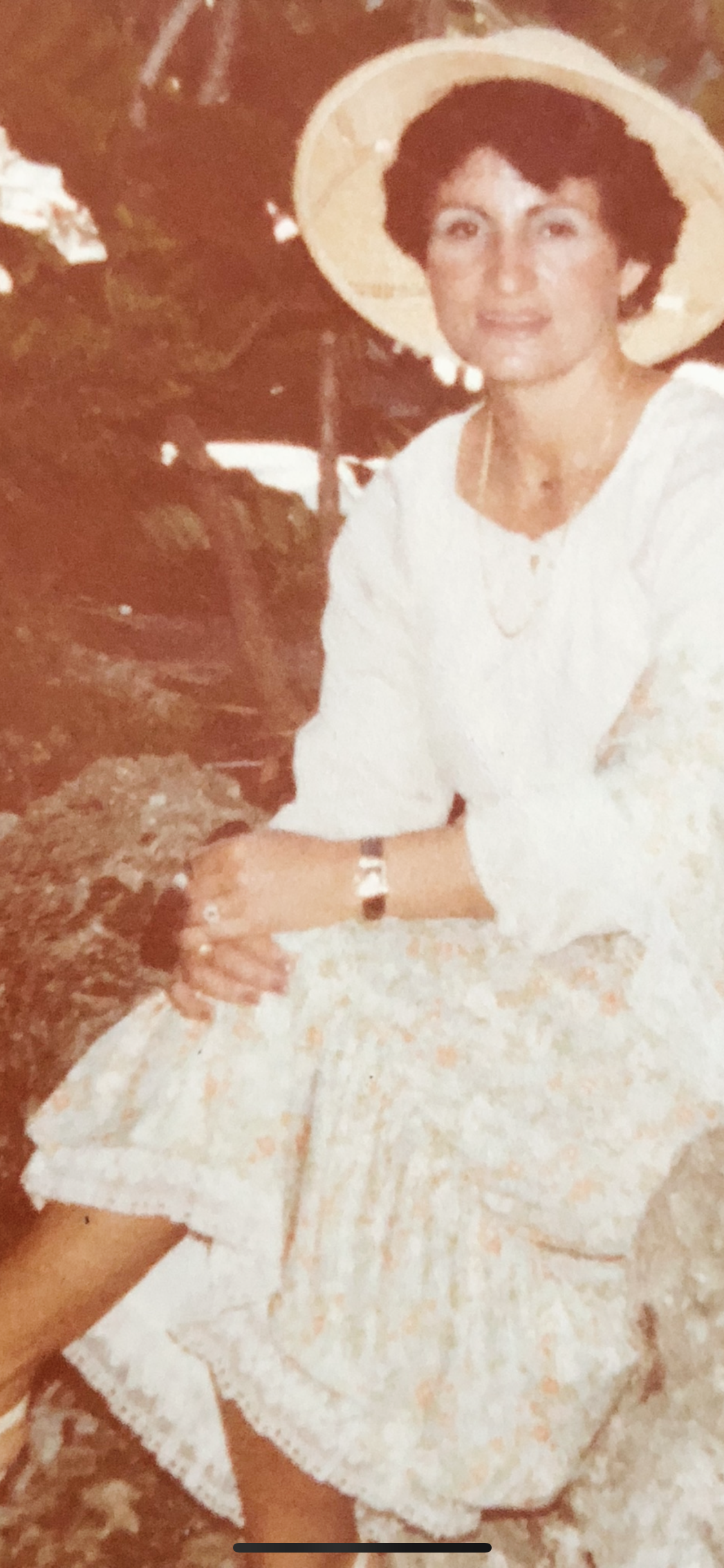 A woman in traditional attire sits gracefully in a serene village, showcasing rich culture.