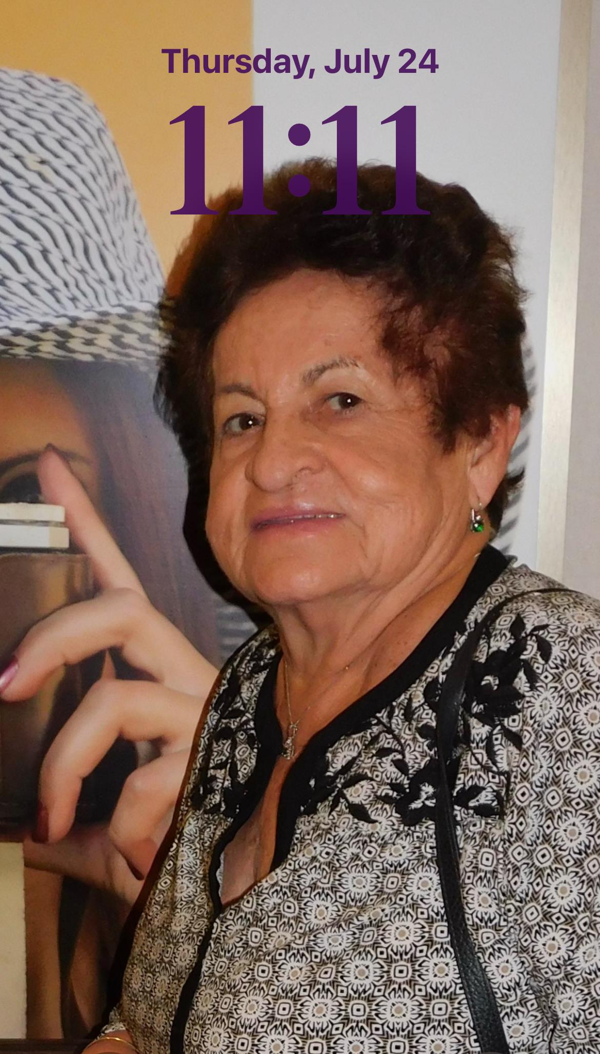 An elderly woman smiles warmly at a gathering in a vibrant community center filled with people.