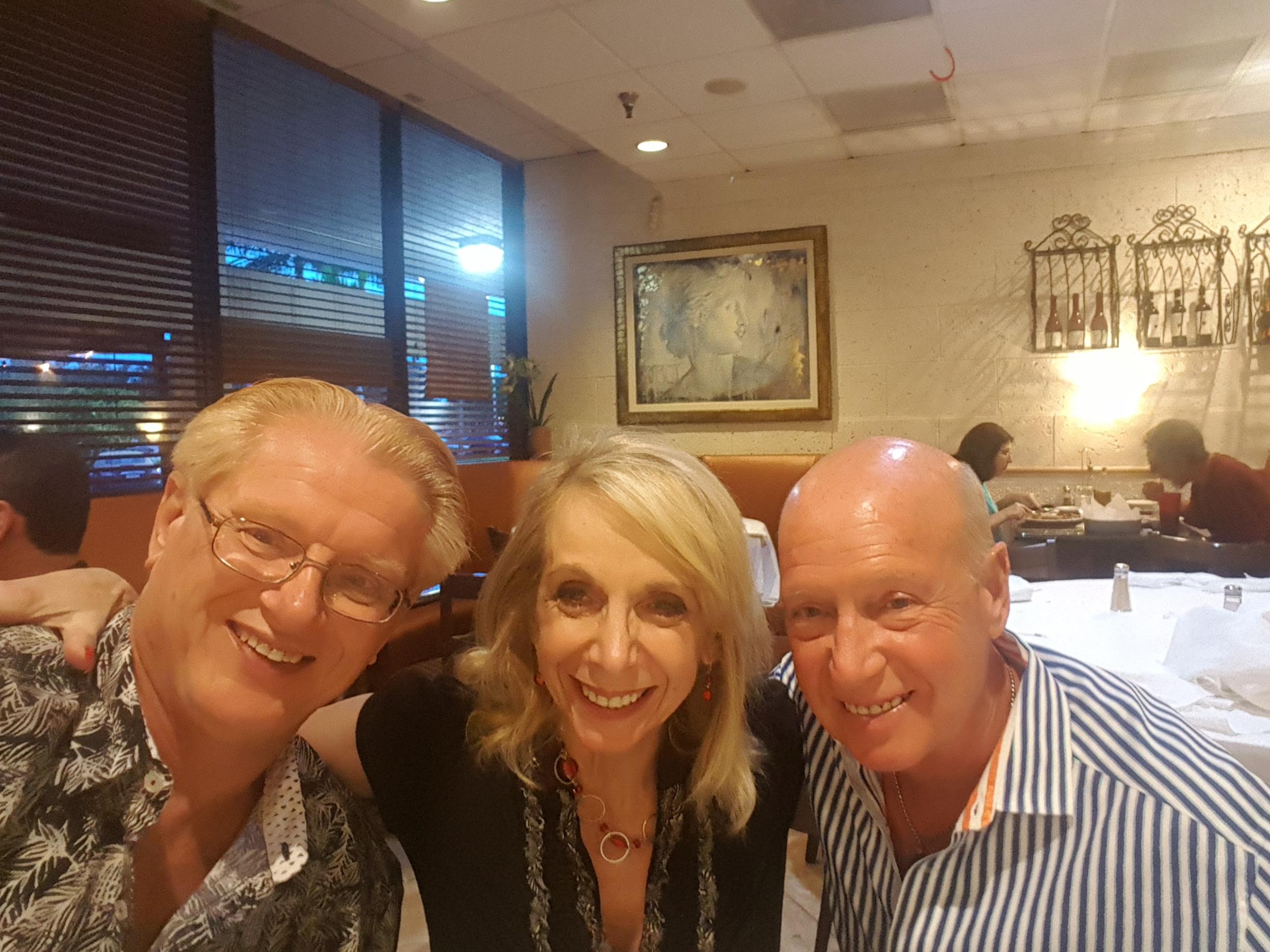 Three friends share laughter and conversation at a table in a cozy restaurant.