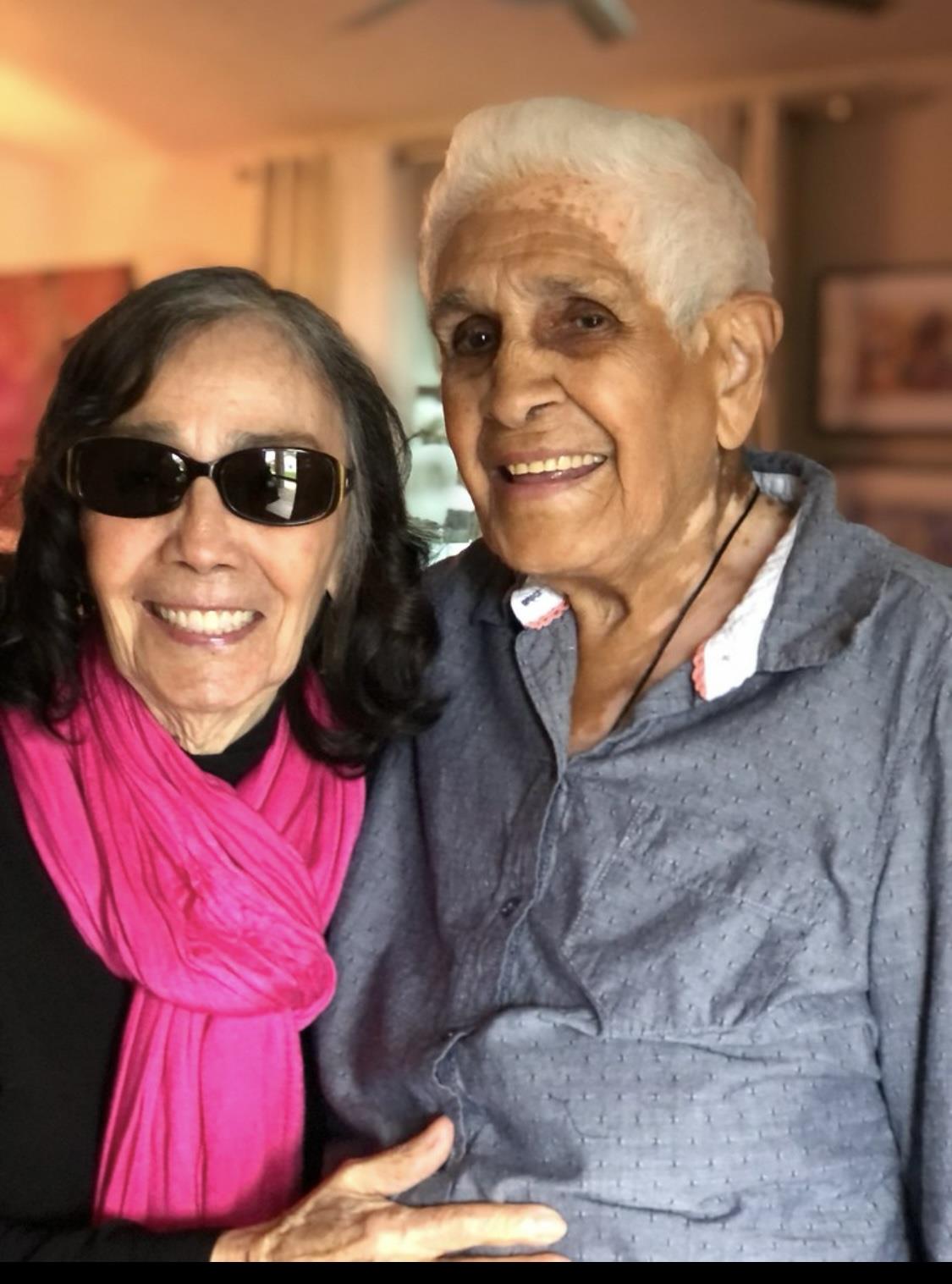 A joyful elderly couple smiles widely while posing together indoors, radiating warmth and affection.