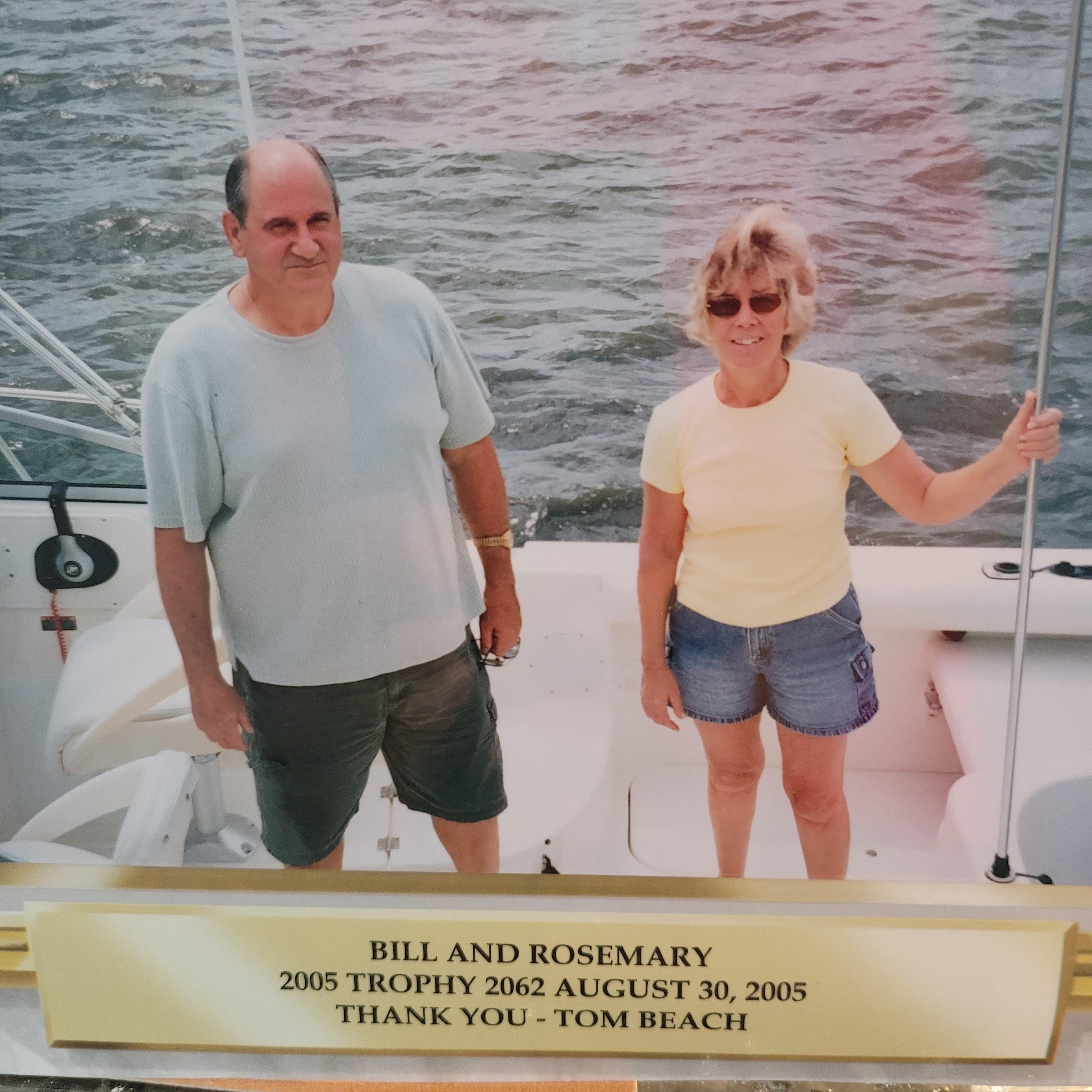 A couple smiles on a boat with their fishing trophy by Tom Beach.