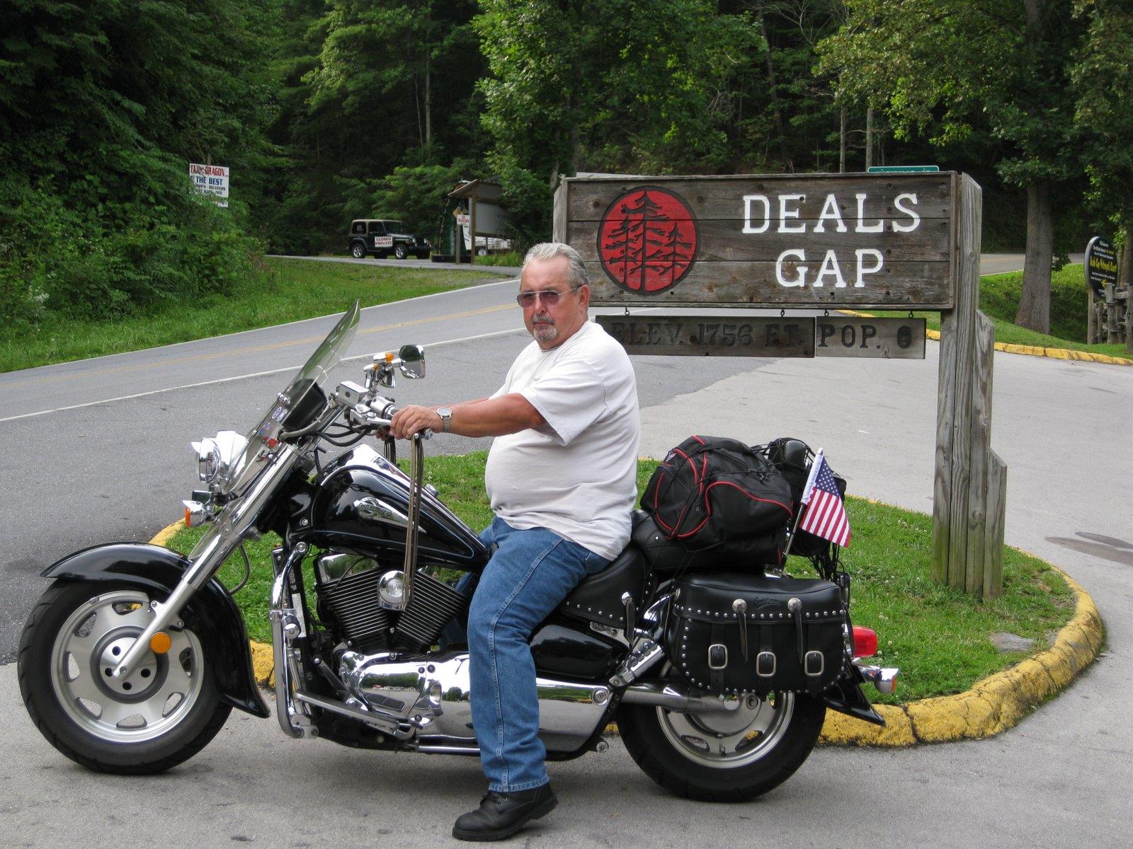A man on a motorcycle enjoys the Smoky Mountains by the Deals Gap sign.