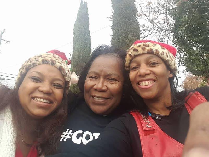 Three friends smile broadly while wearing Santa hats at a cheerful winter gathering.