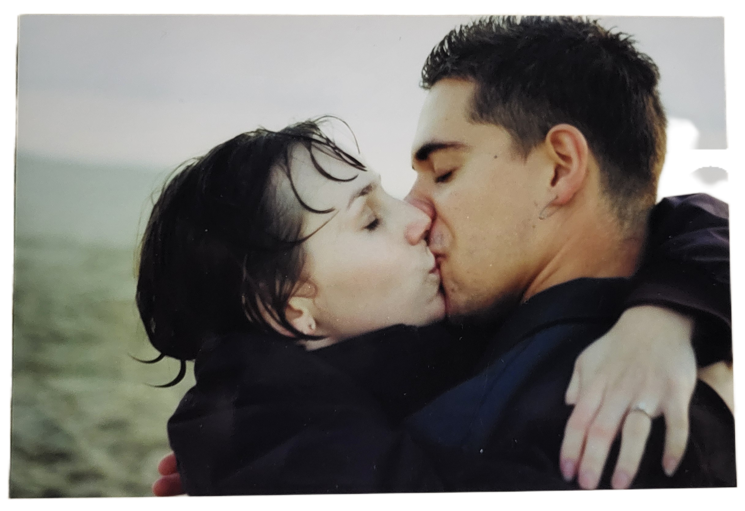 A couple embraces and kisses deeply, enjoying a moment of intimacy despite the rain around them.