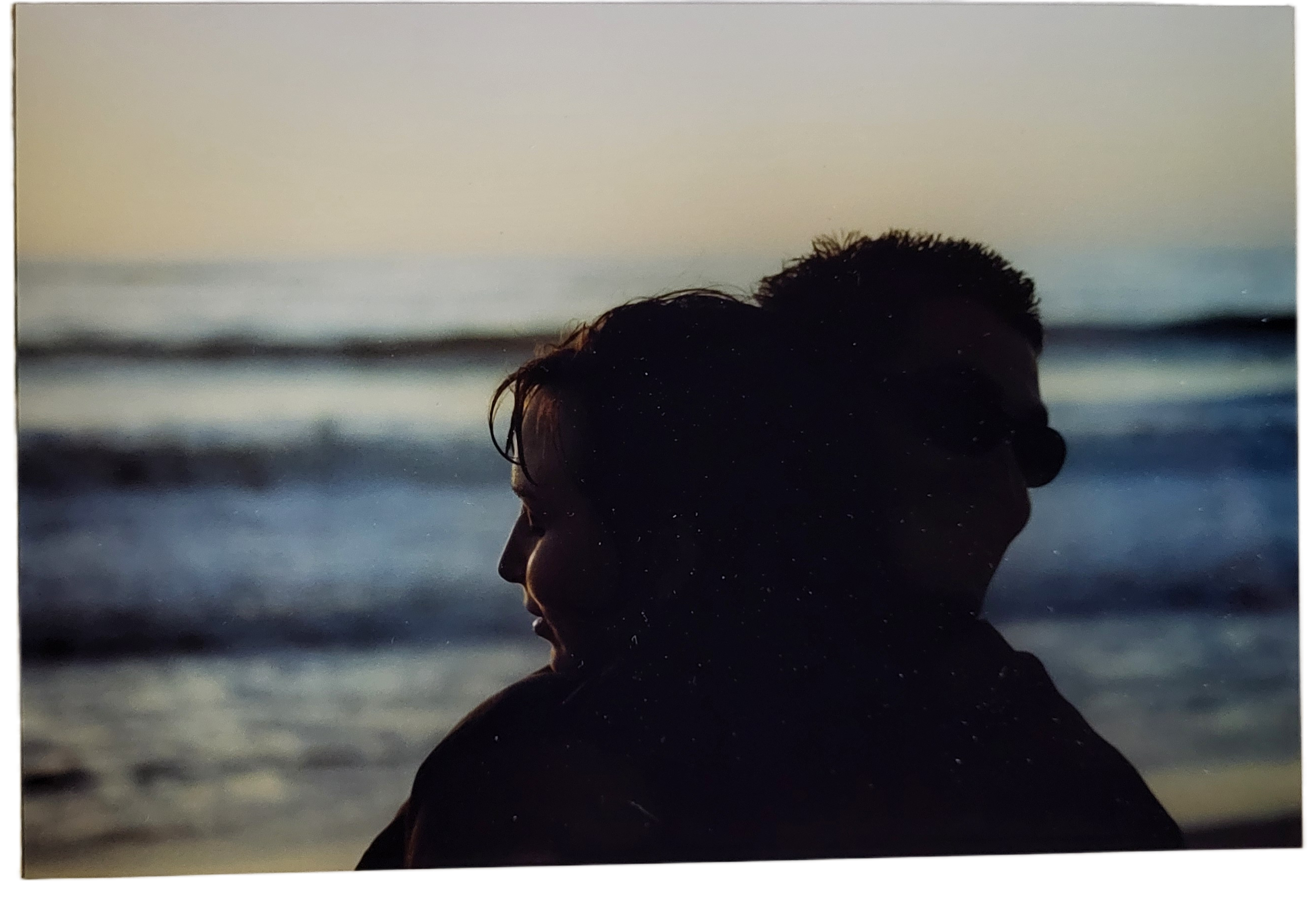 A couple sits close at sunset on the beach, reflecting their bond and calmness.