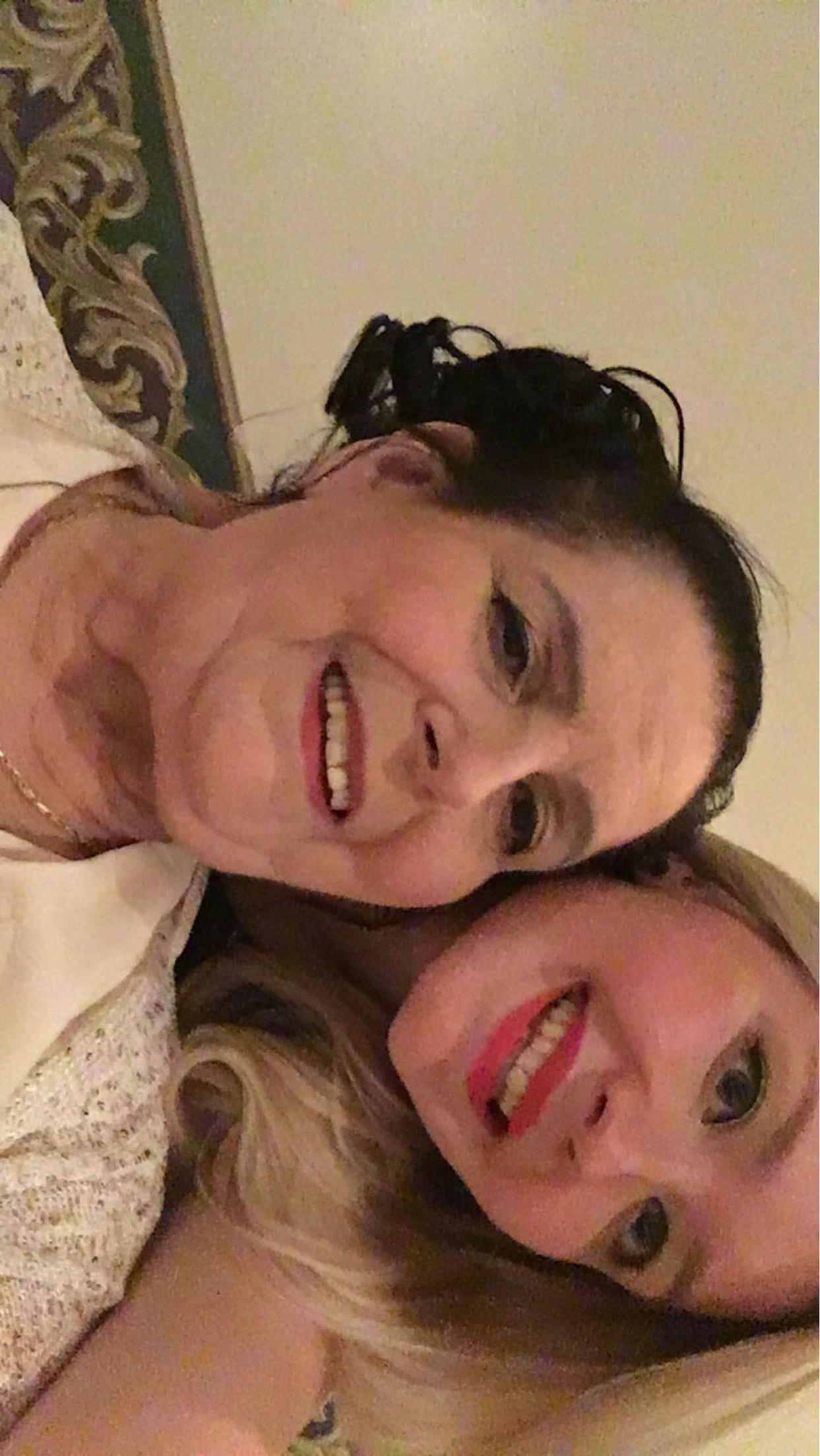 Two women smile happily while posing close together, enjoying a joyful family gathering.