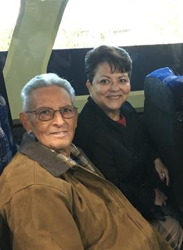 Two happy individuals smile at each other while sitting on a bus, enjoying their journey together.