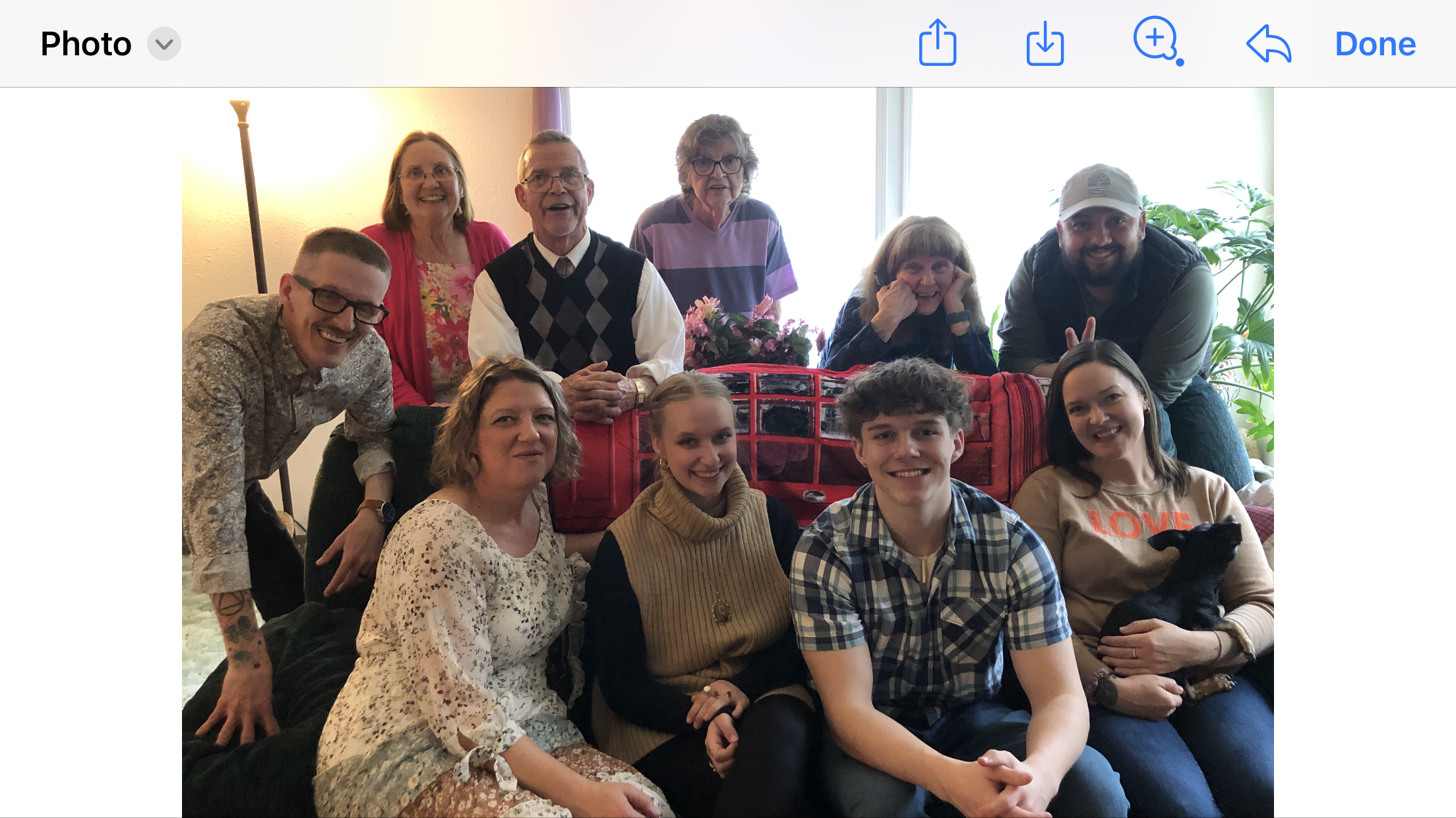 A group of family members poses together, smiling and celebrating in a warm living room.