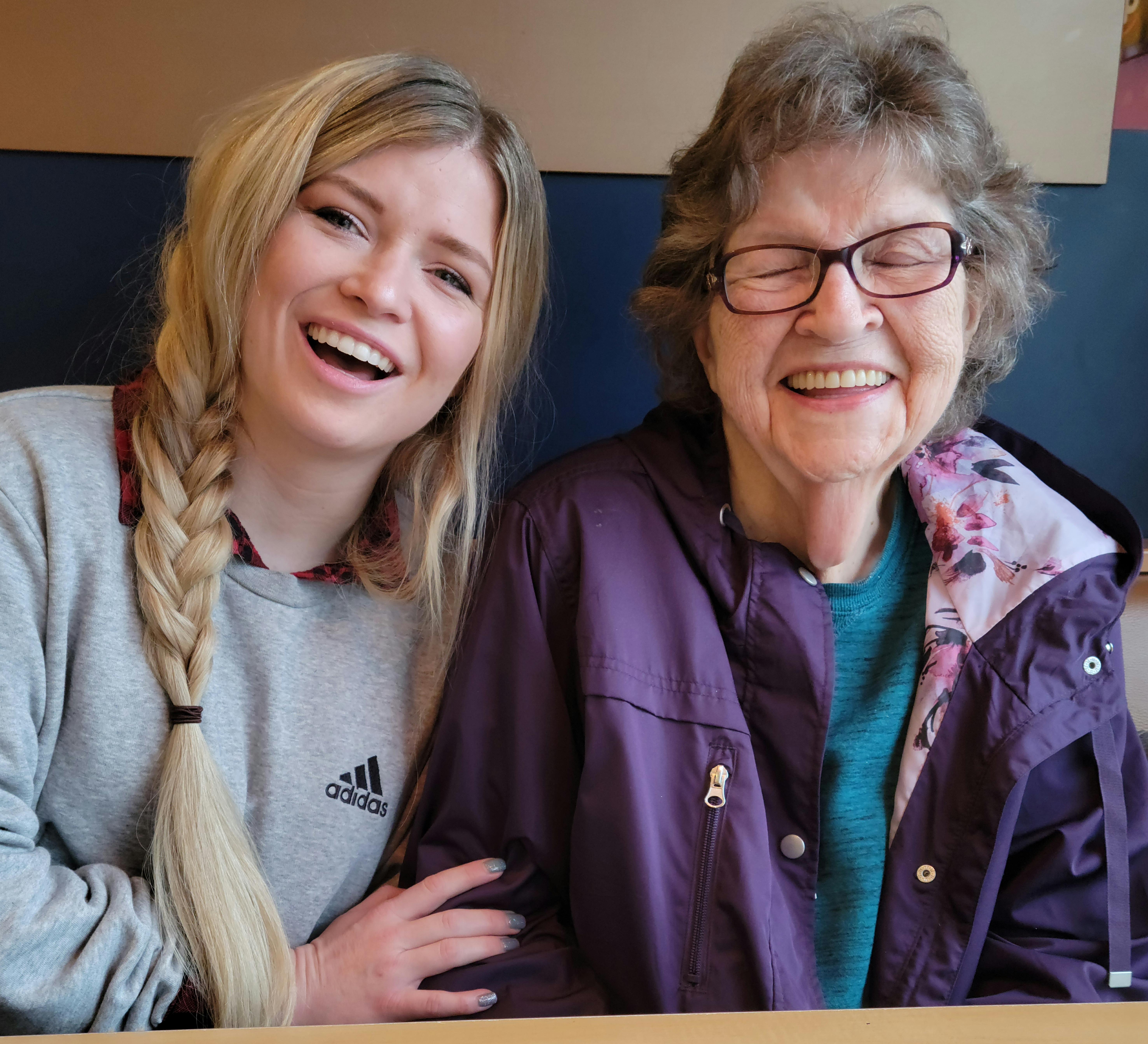 Two women share laughter and smiles together, capturing a heartwarming moment in a cafe.