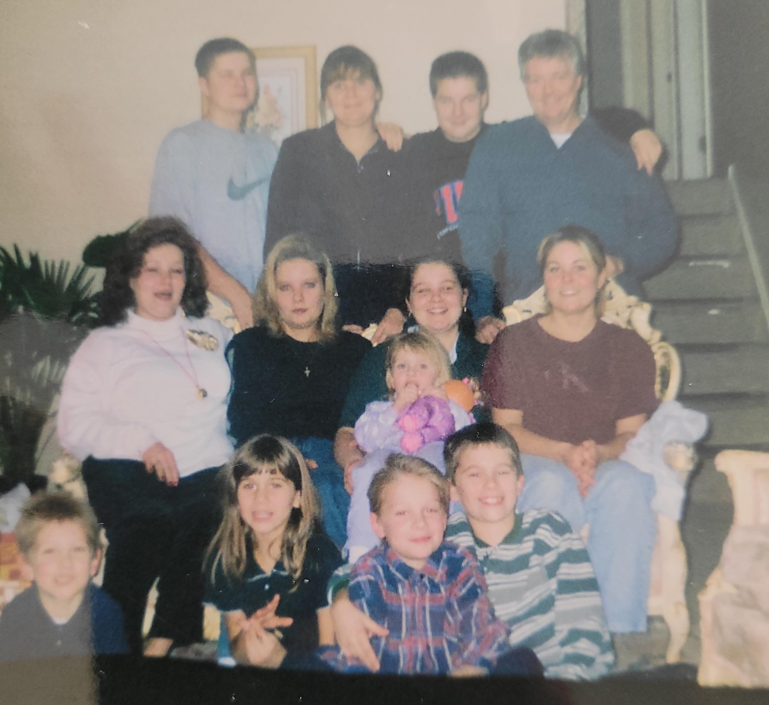 Group of family members of varying ages smiling and sitting together in a cozy living room setting.