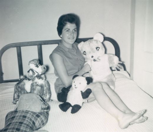 A woman sitting on a bed with stuffed animals