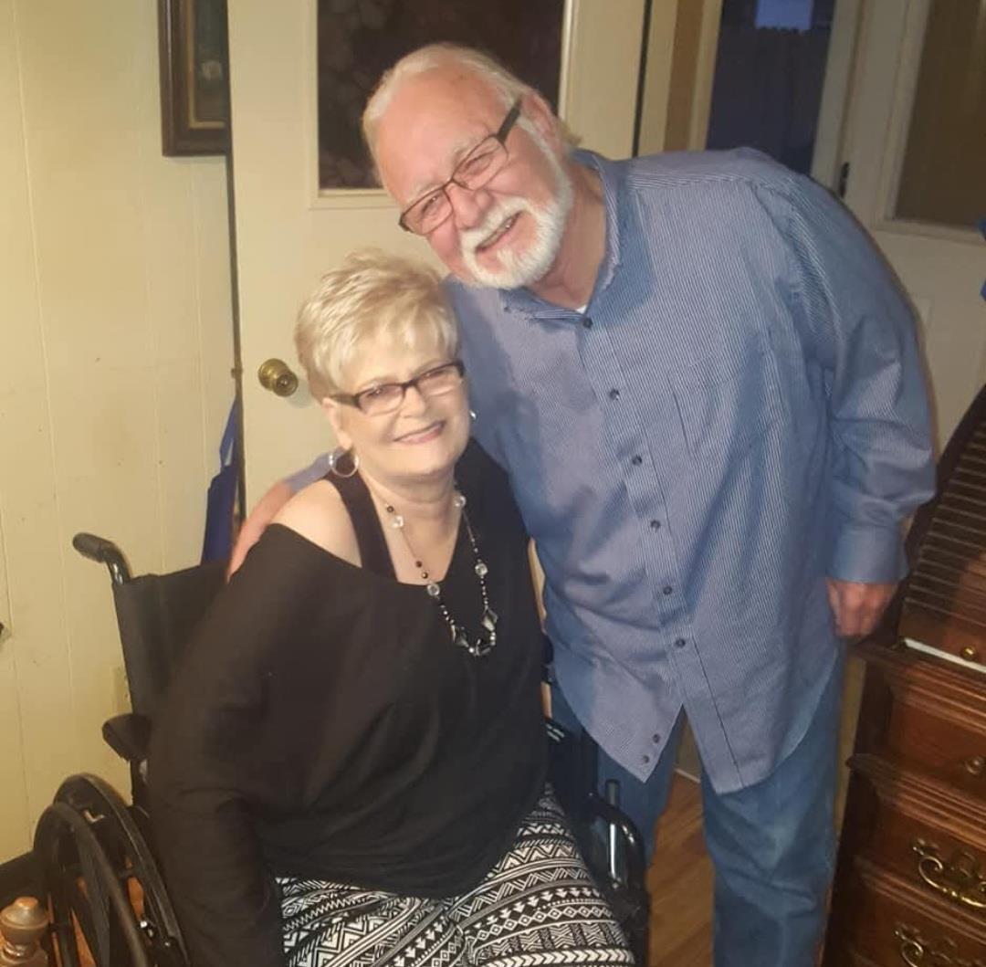 Two individuals are smiling happily while posing for a photo at home, enjoying their time together.