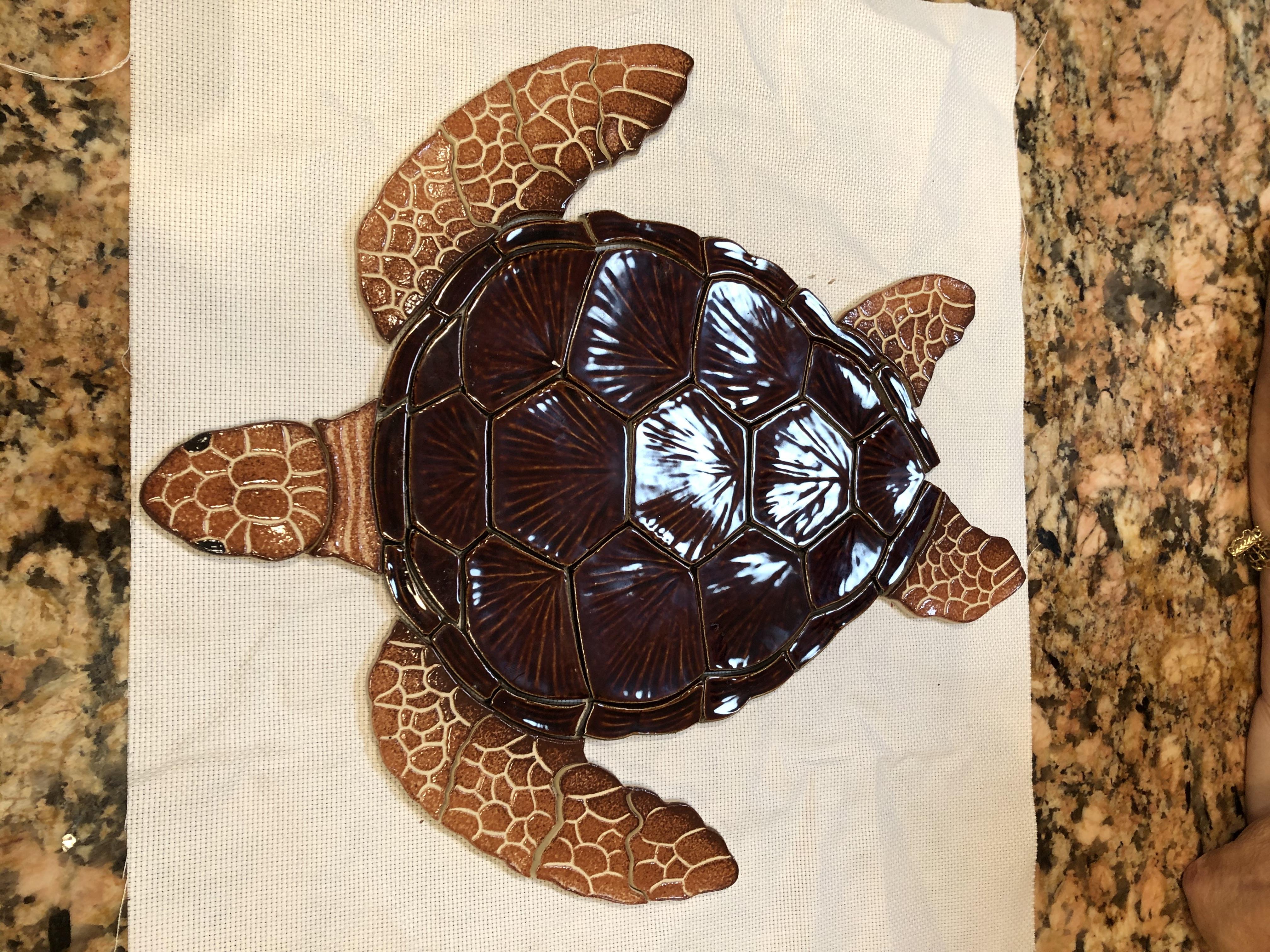 Brown turtle design made from ceramic rests on a light surface in a kitchen setting.