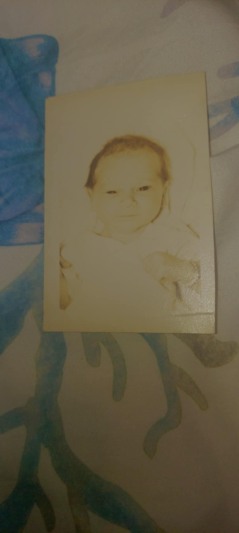 A baby sits in soft light, surrounded by a warm, textured blanket, radiating tranquility.