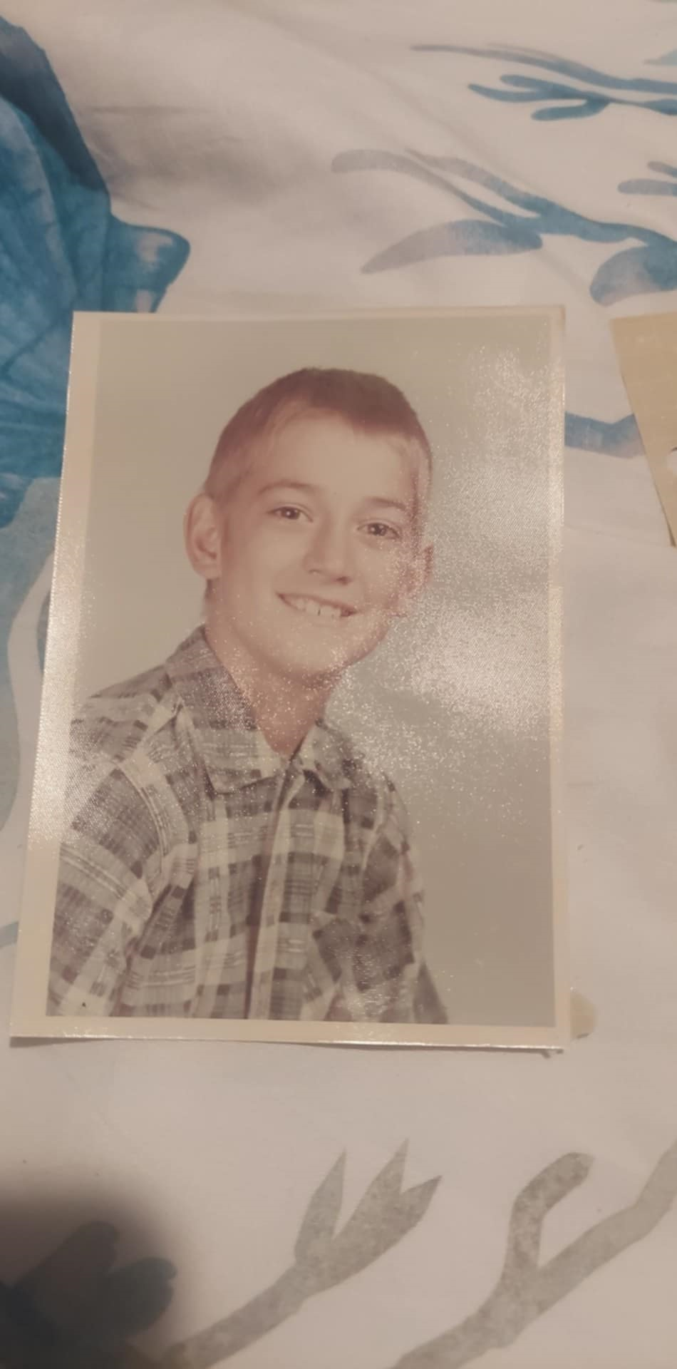 A smiling boy in a plaid shirt poses in a classic portrait.